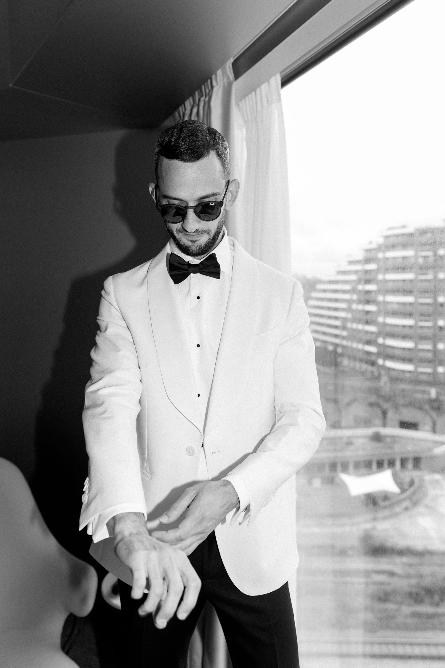 Sequence of a person in white tuxedo and bowtie adjusting their outfit.