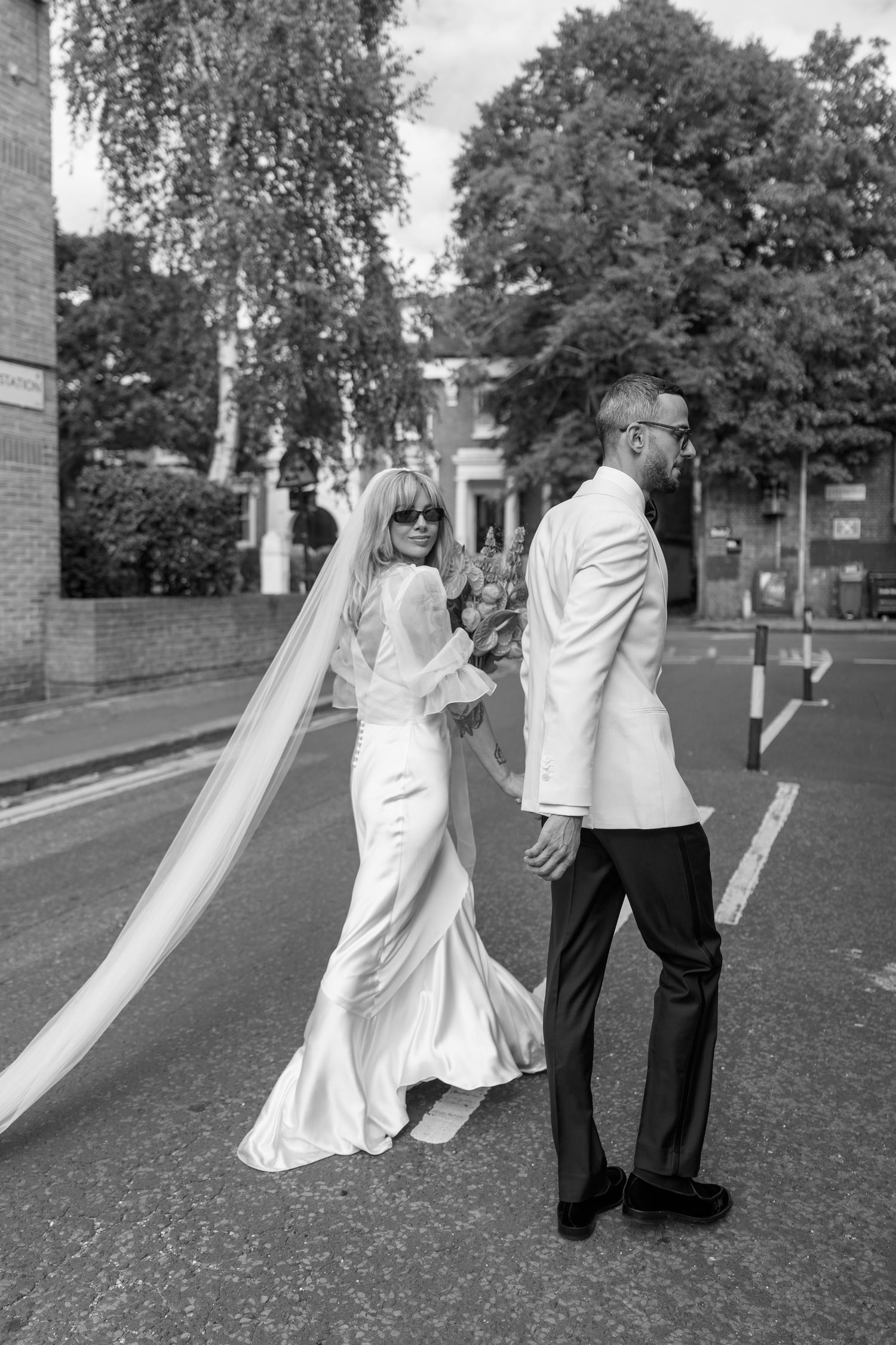 Black and white wedding photos showing playful moments with a flowing veil in an outdoor setting.