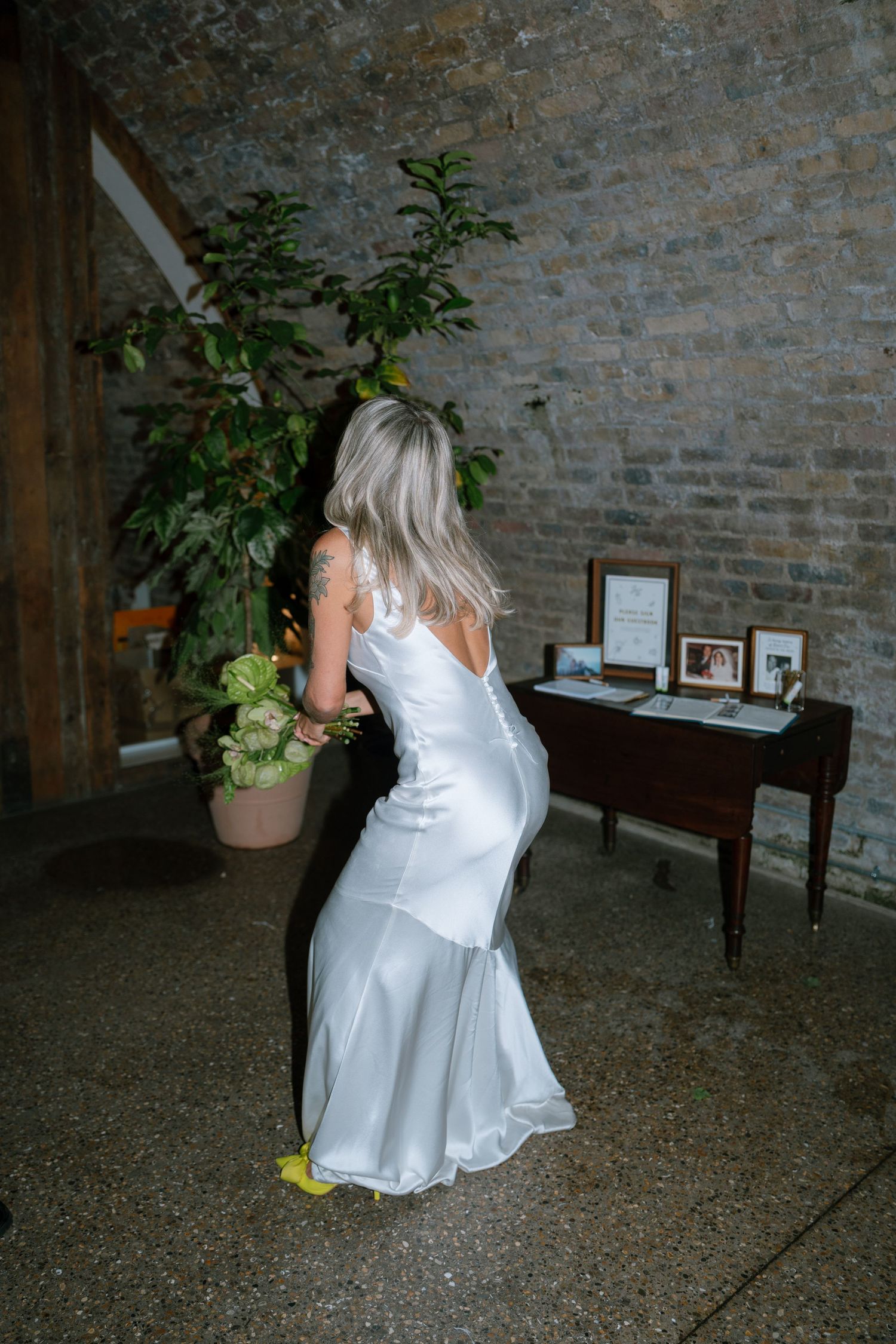 A child in a white dress twirls and plays on a stone floor during a wedding reception.