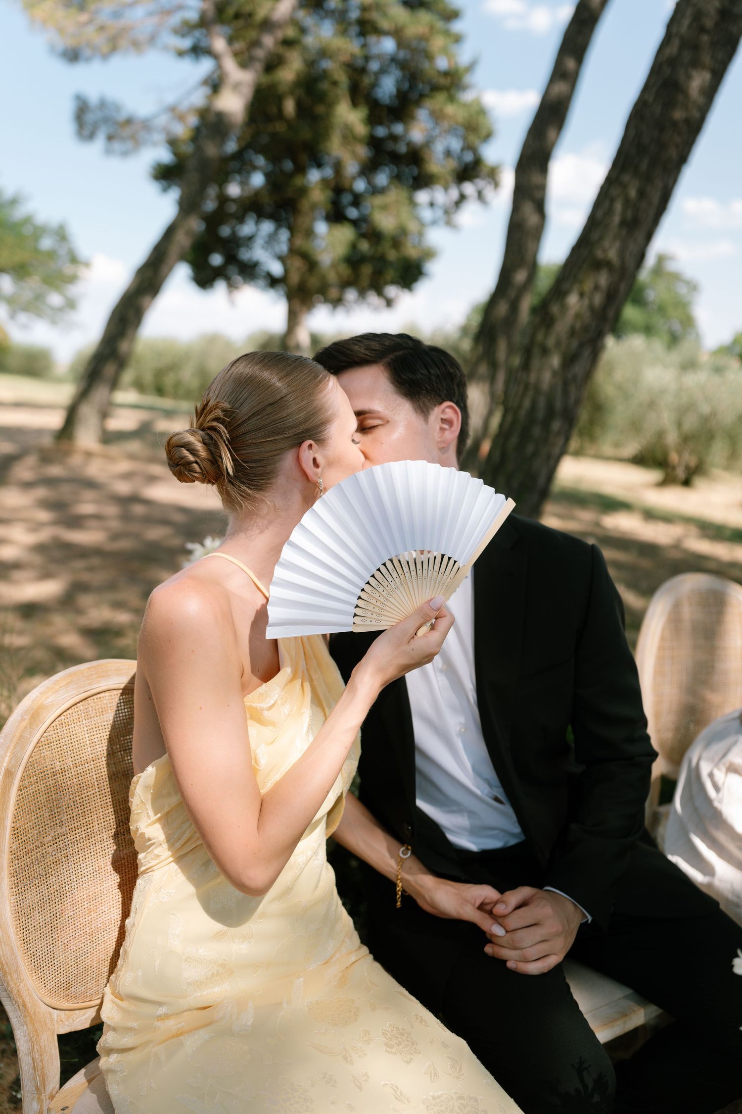 Couple sharing romantic moment behind decorative white hand fan.
