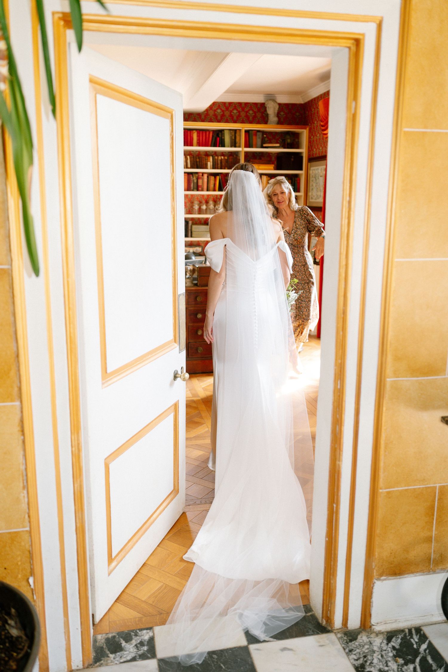 White wedding dress displayed in a hallway with gold-trimmed walls.