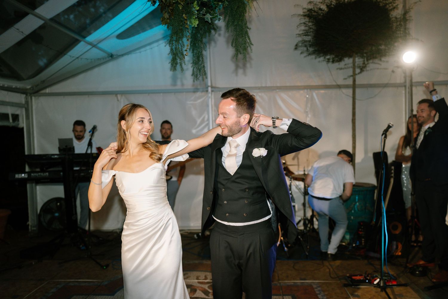 A couple performs an energetic dance move during their wedding reception.