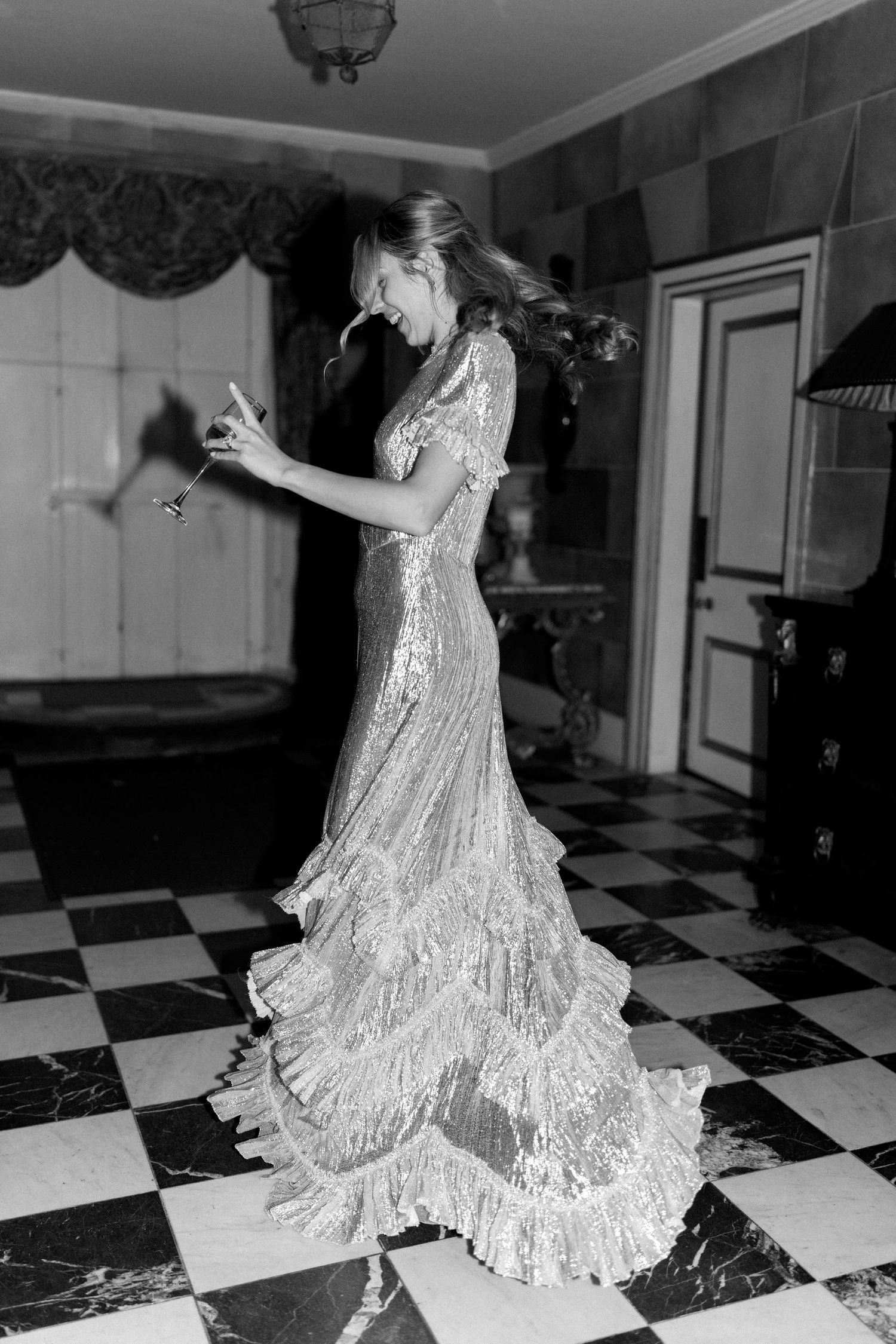 A dancer in a shimmering gown moves gracefully across a geometric floor pattern.