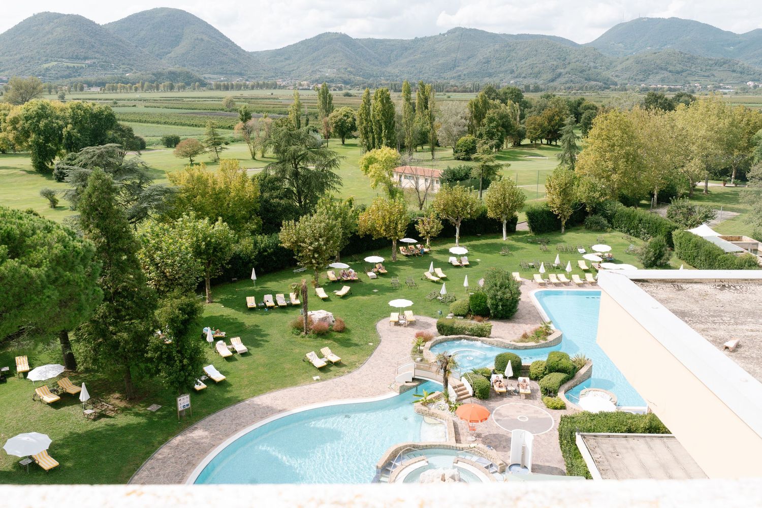 Luxury resort pool area surrounded by loungers with mountain views.