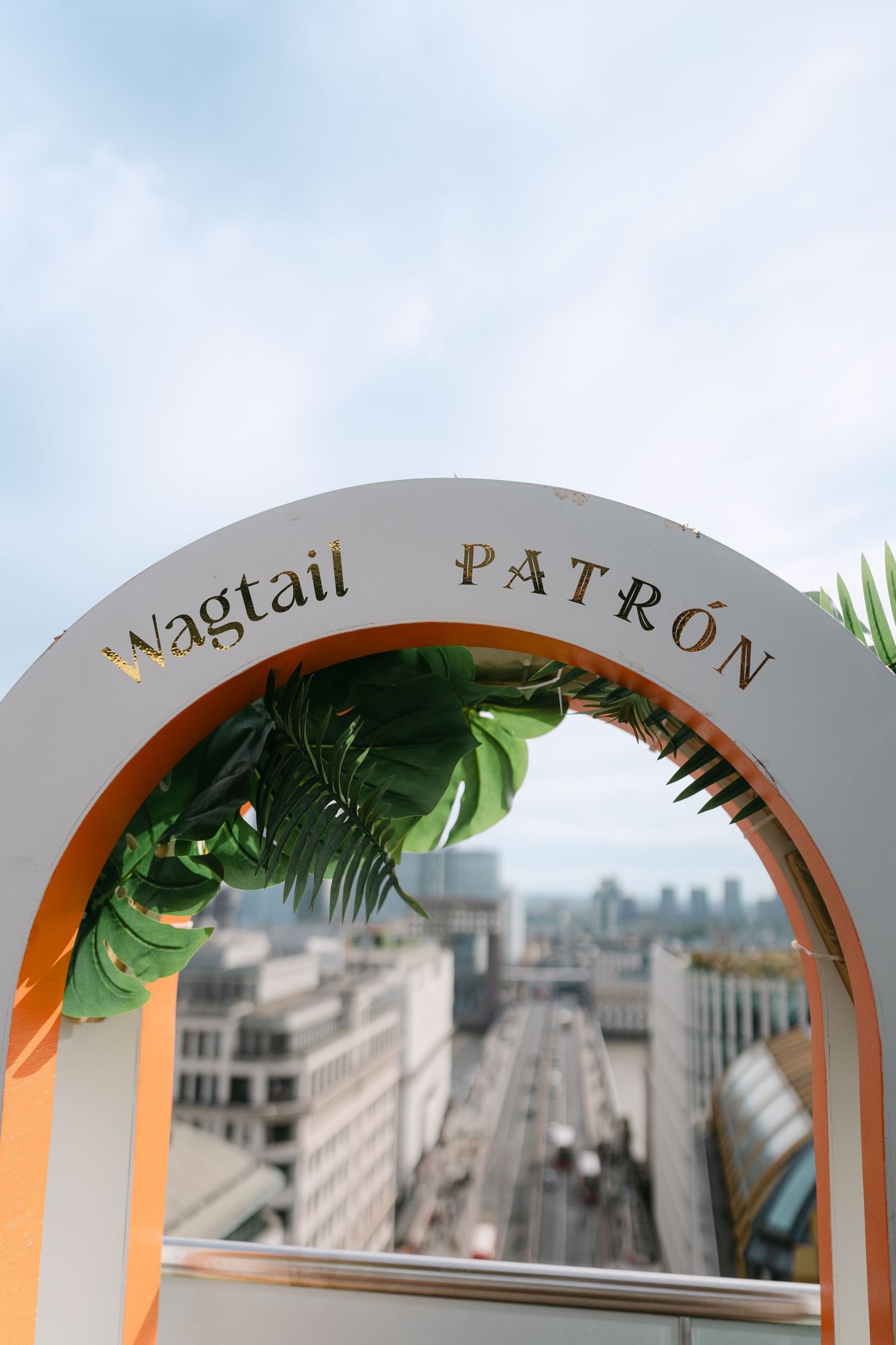 Decorative arched signage with text against a city skyline backdrop.