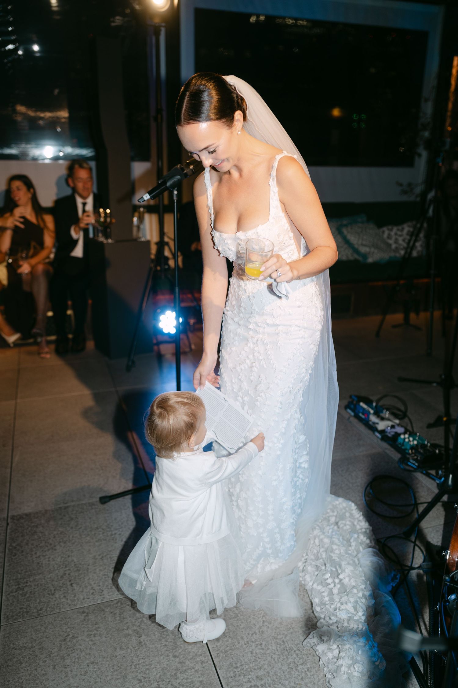 A sweet moment between a bride in white dress and small child at a wedding reception.