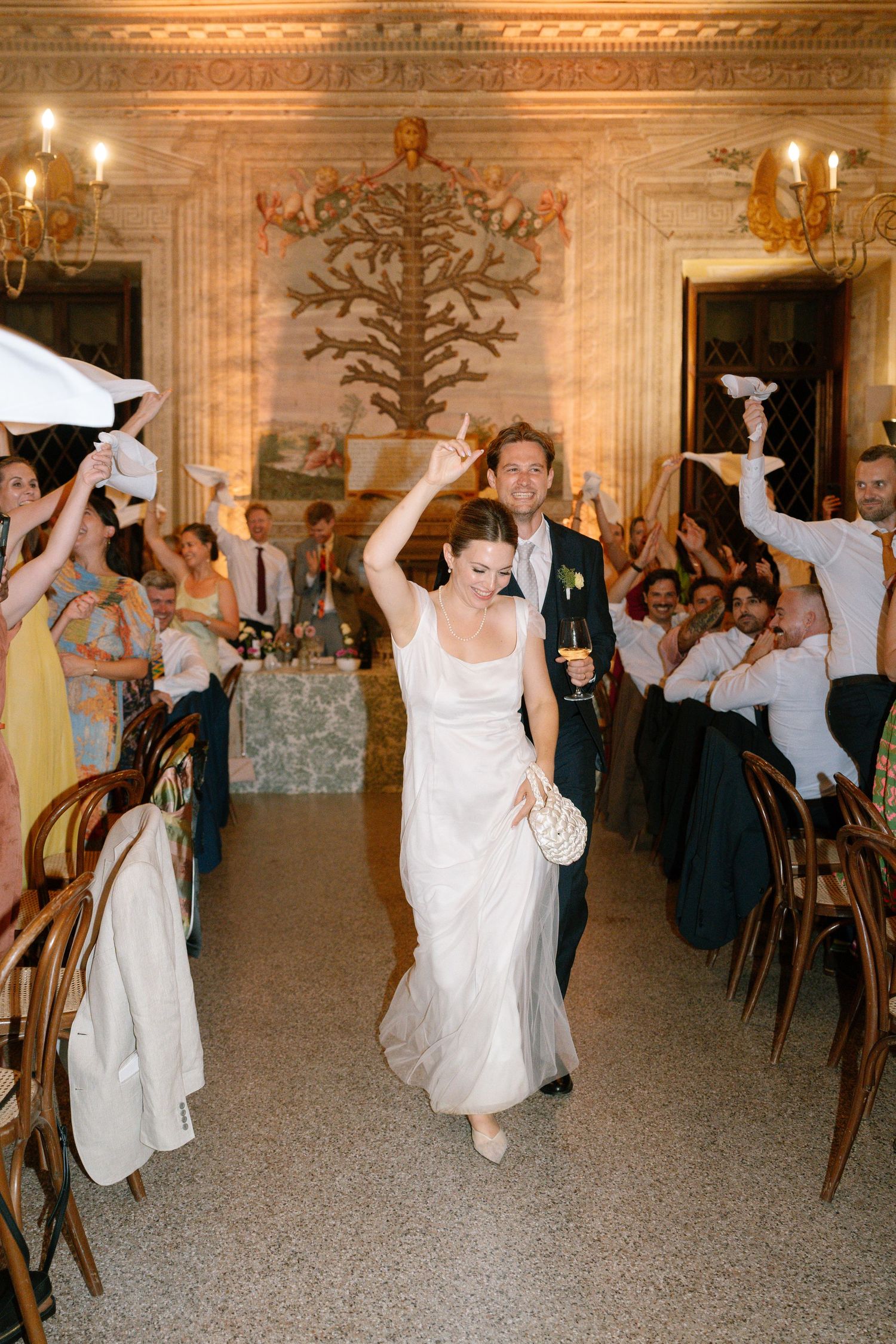 Joyful celebration with guests waving napkins during a festive ballroom reception.