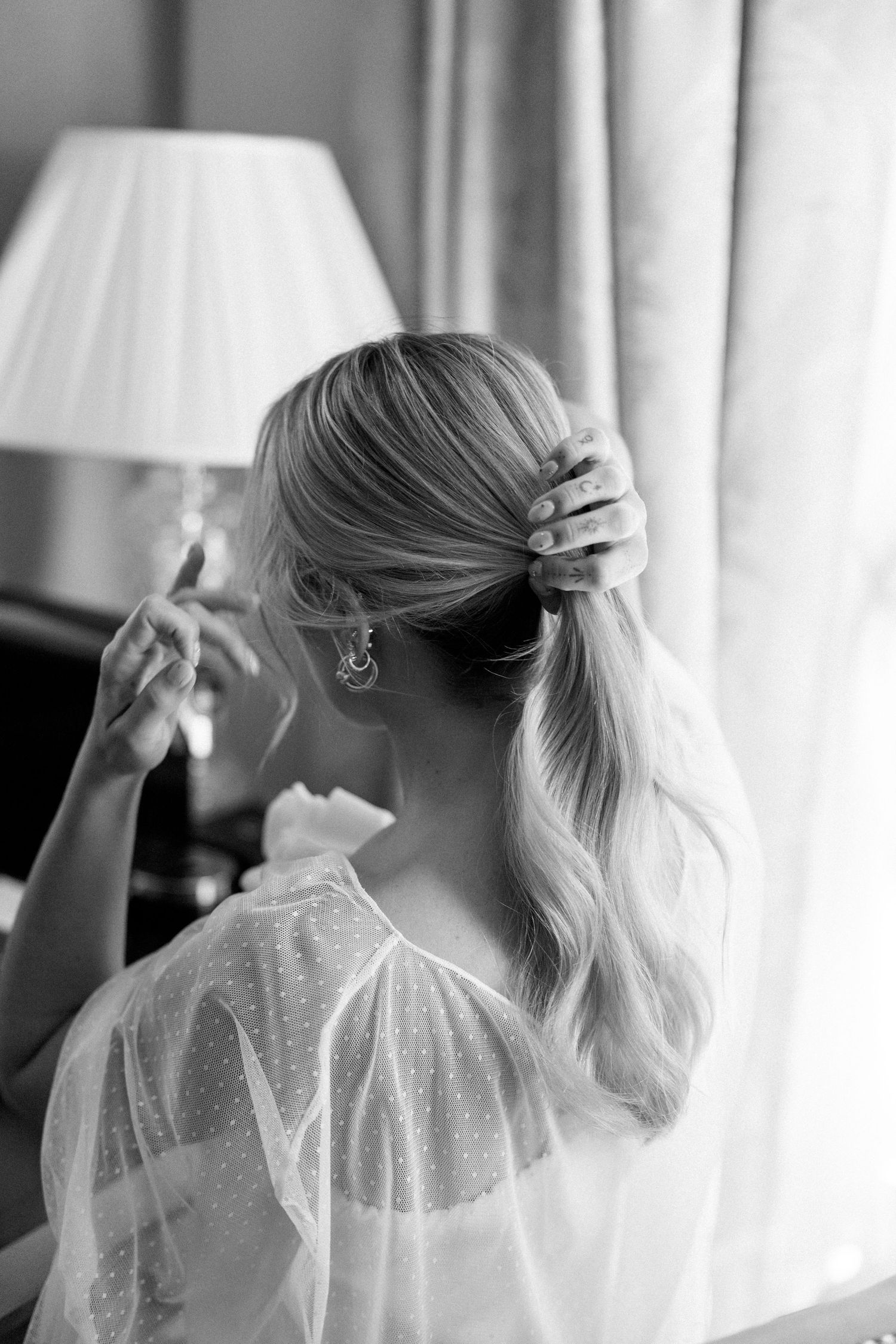 Elegant bridal preparation moment captured in black and white at dressing table.