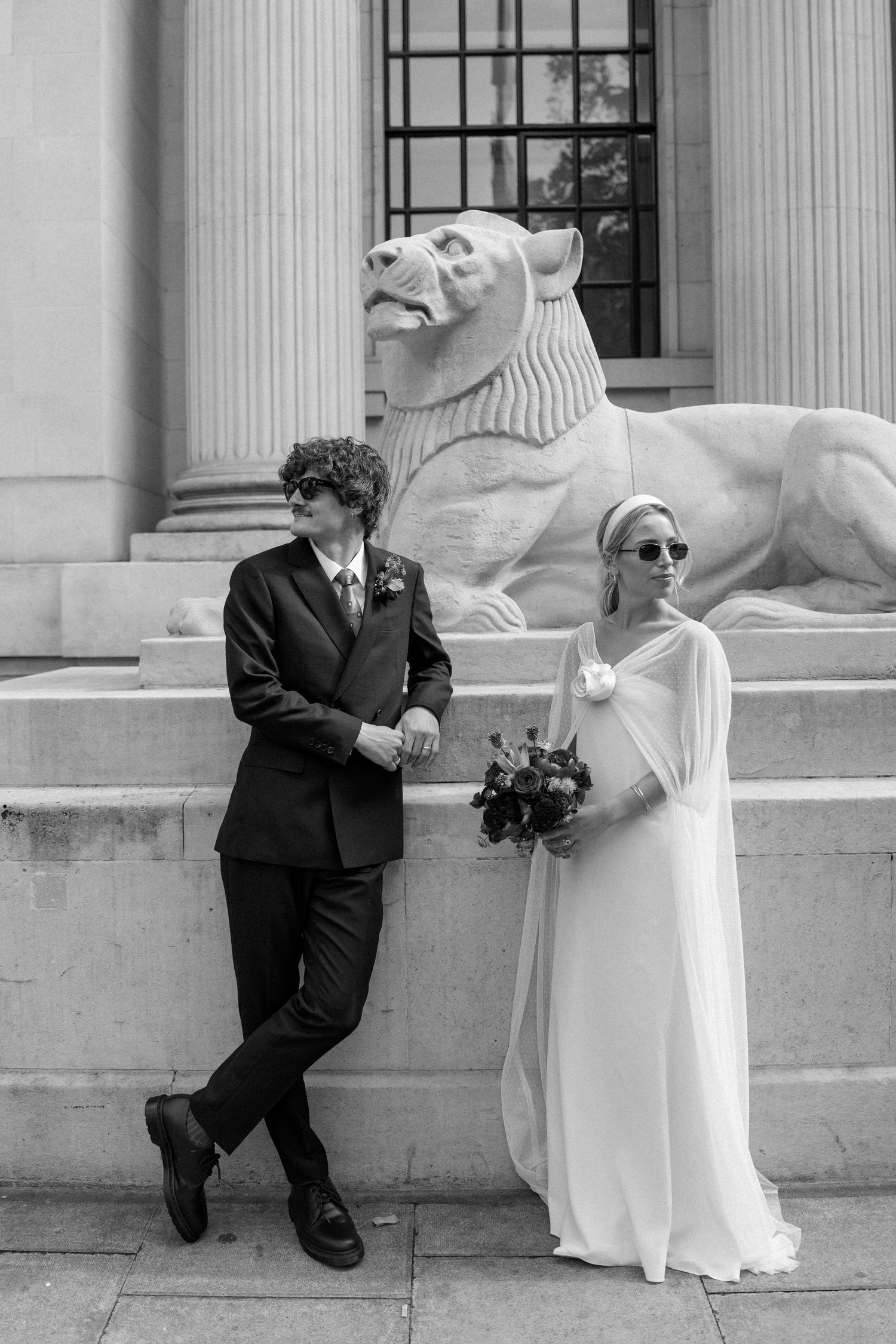 Playful wedding photo series showing couple interacting with classical stone architecture.