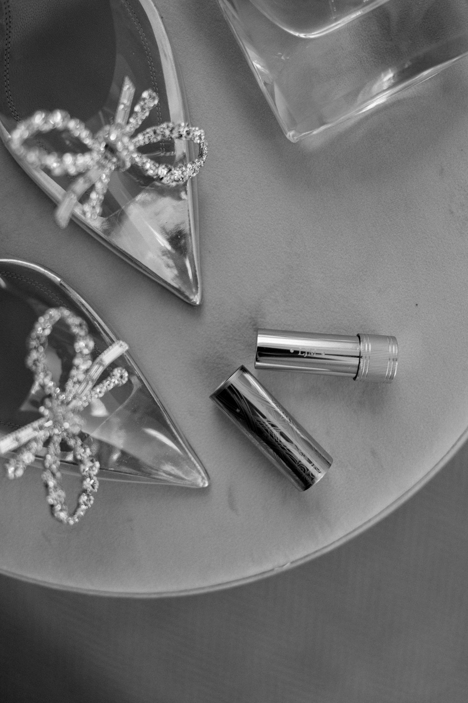 Black and white photo of sparkly accessories and metallic items on a reflective surface.