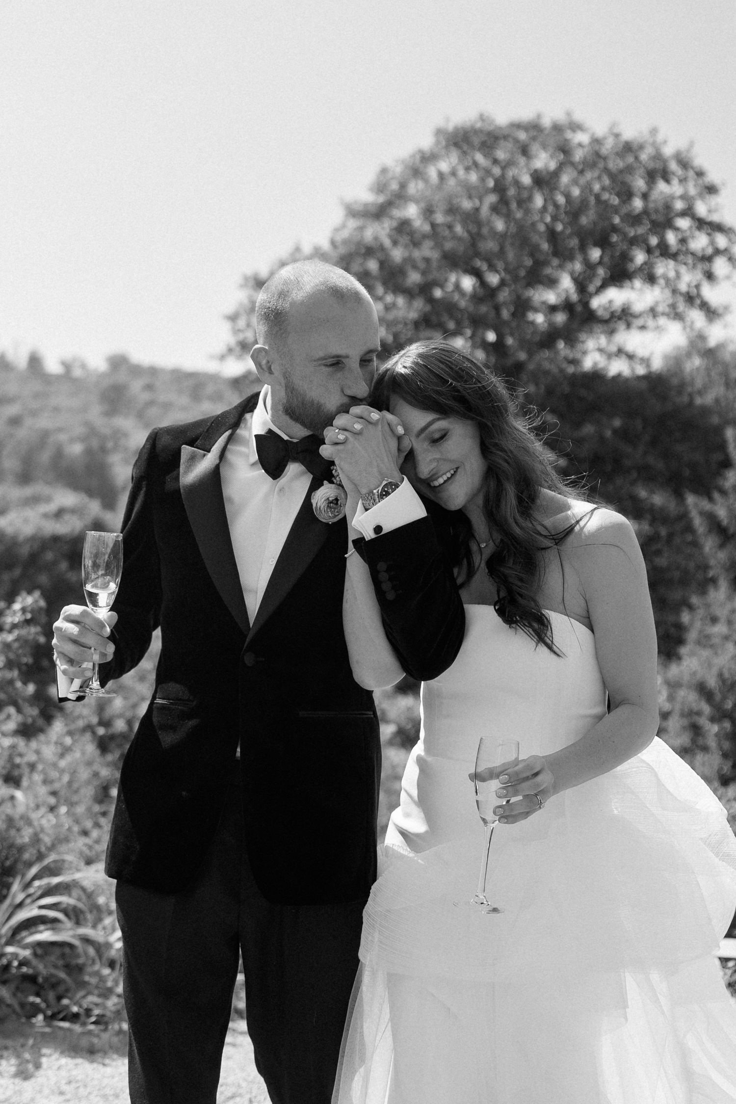 A romantic black and white wedding photo series showing a couple sharing intimate moments in an outdoor setting.