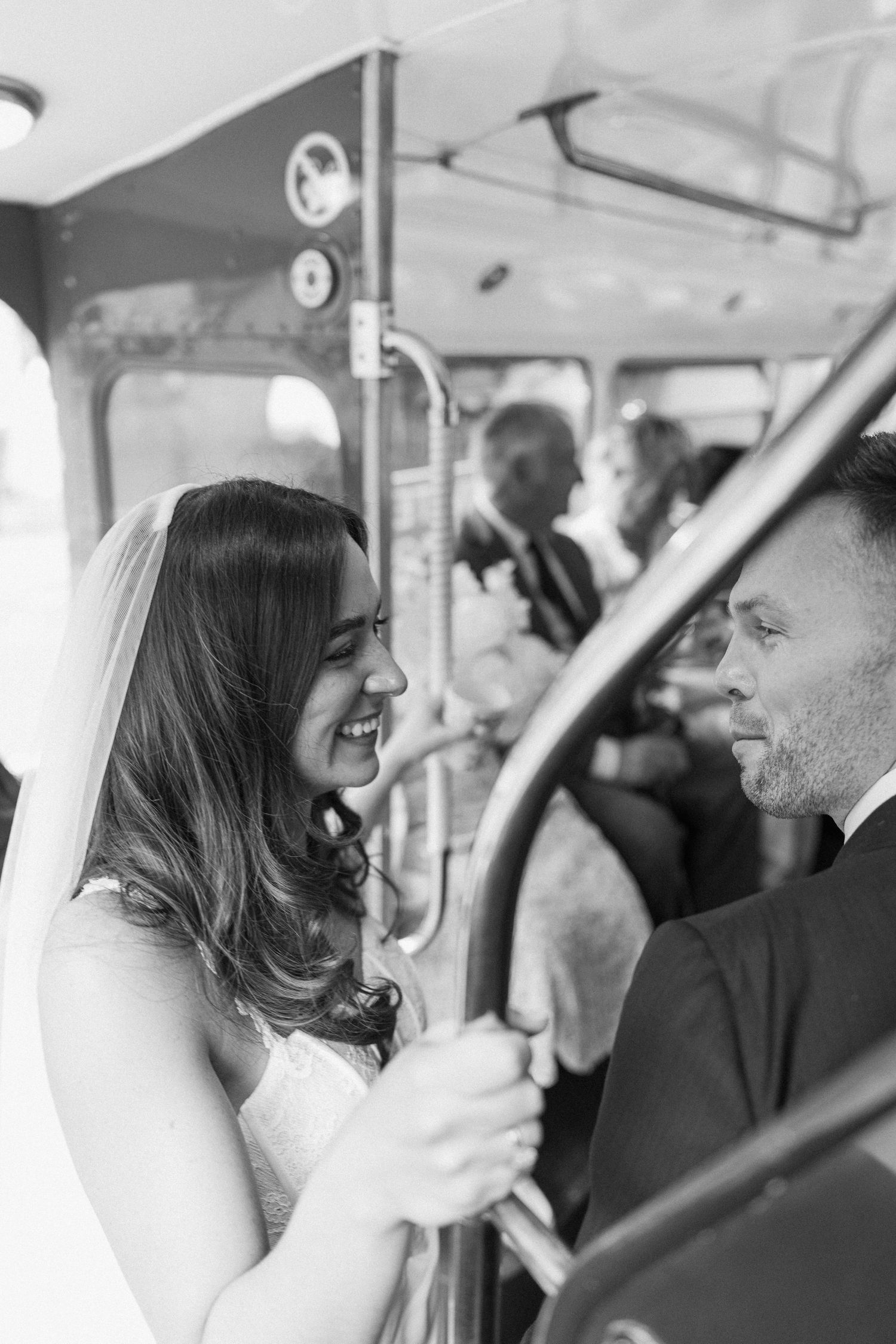 Bride and groom share a joyful moment on a vintage bus during their wedding day.