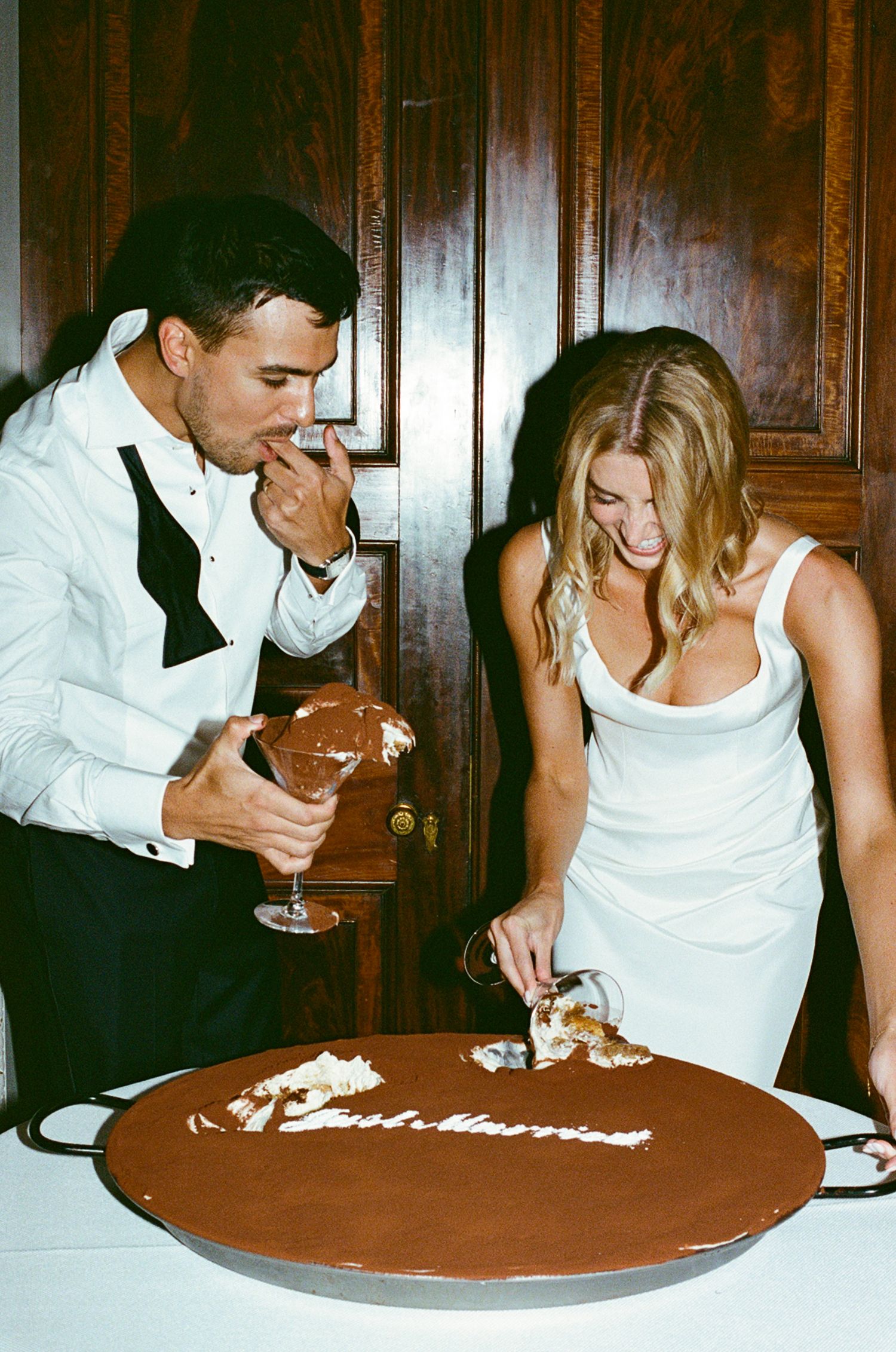 Newlywed couple cutting a chocolate wedding cake inscribed with Just Married at their elegant reception.