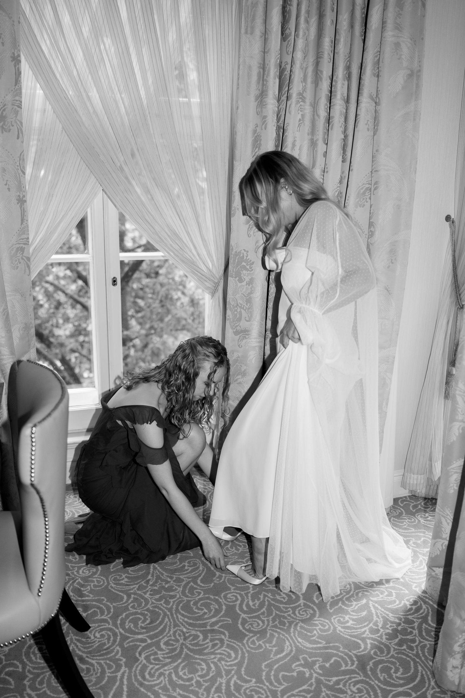 Wedding dress preparation scene with white gown and helper in getting ready room.