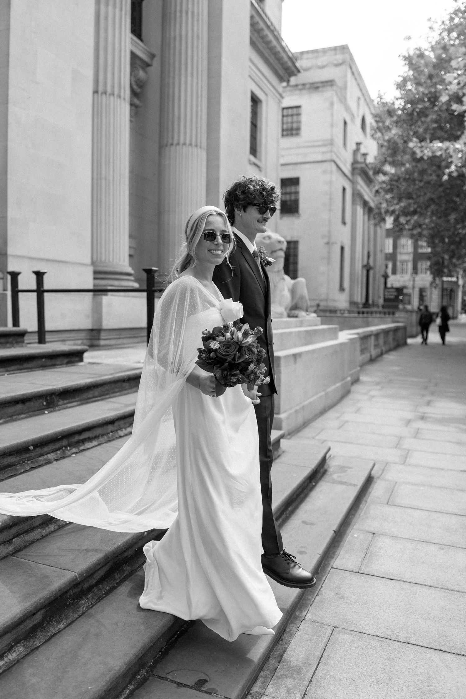 Black and white wedding photos showing dynamic movement and interaction on a columned building's steps.