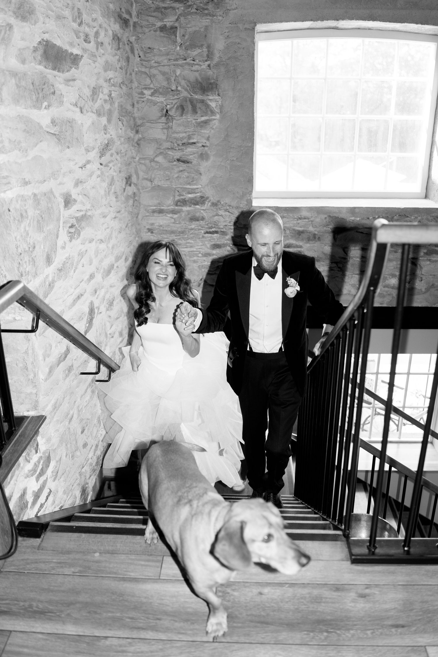 Playful wedding party poses on rustic stone staircase.