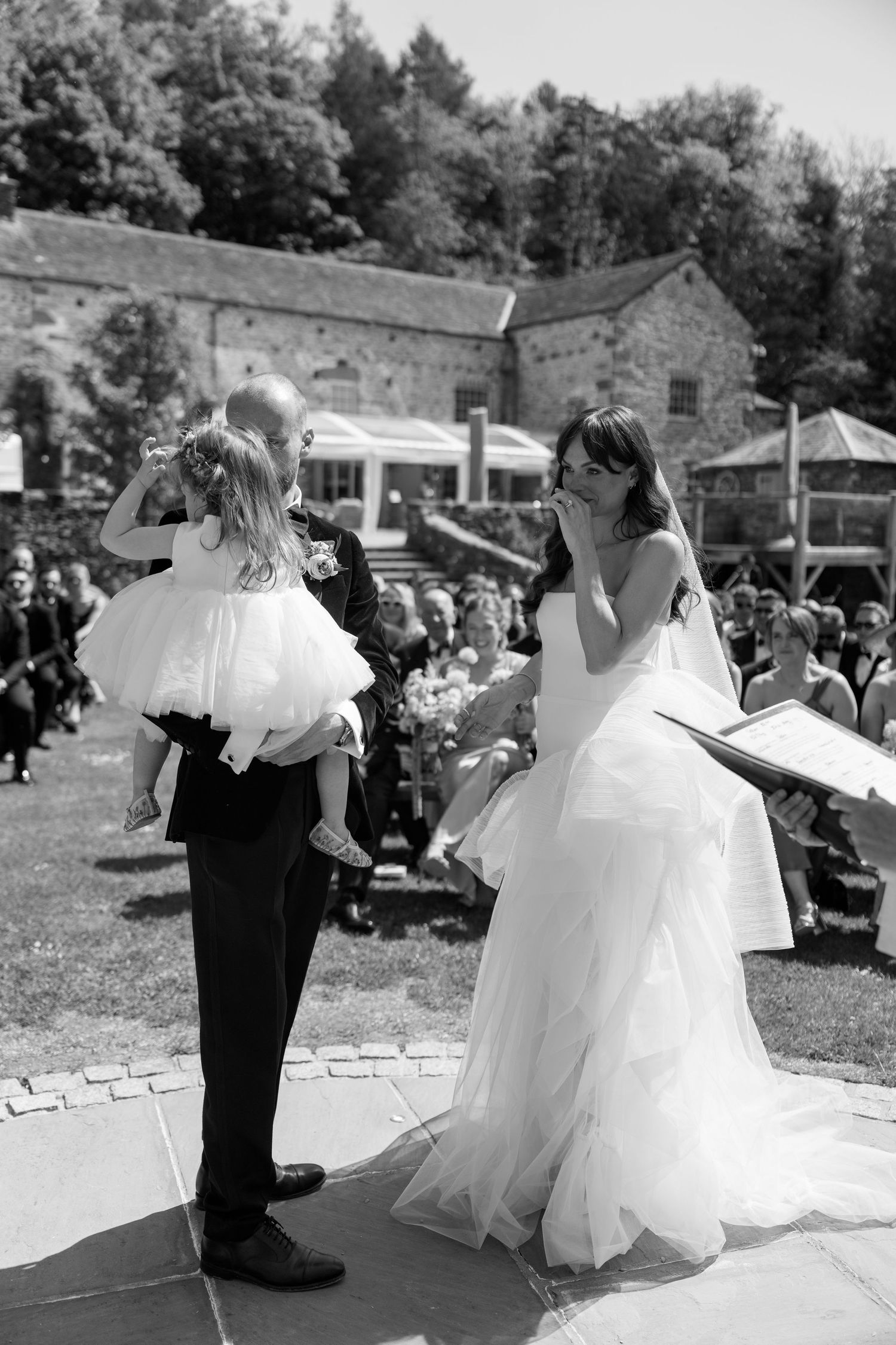 Wedding couple dances energetically on outdoor patio surrounded by guests.
