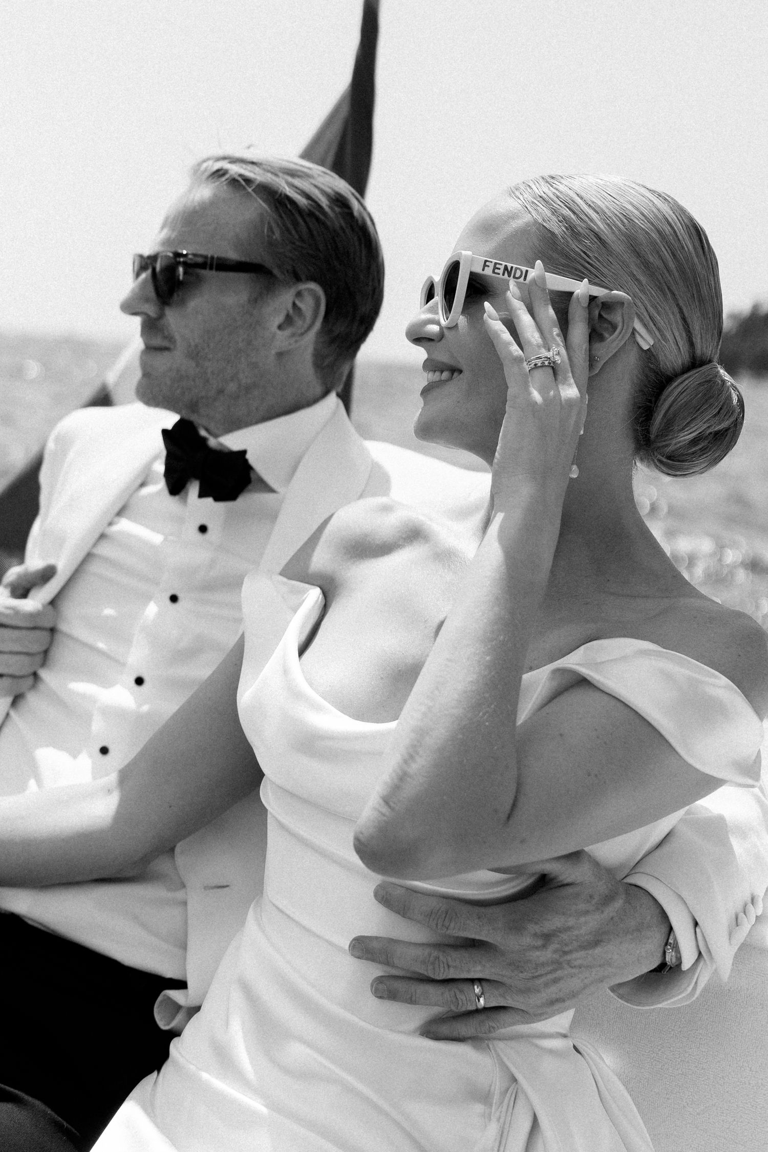 Elegant black and white wedding photo of couple in formal attire, woman in off-shoulder gown with Fendi sunglasses.