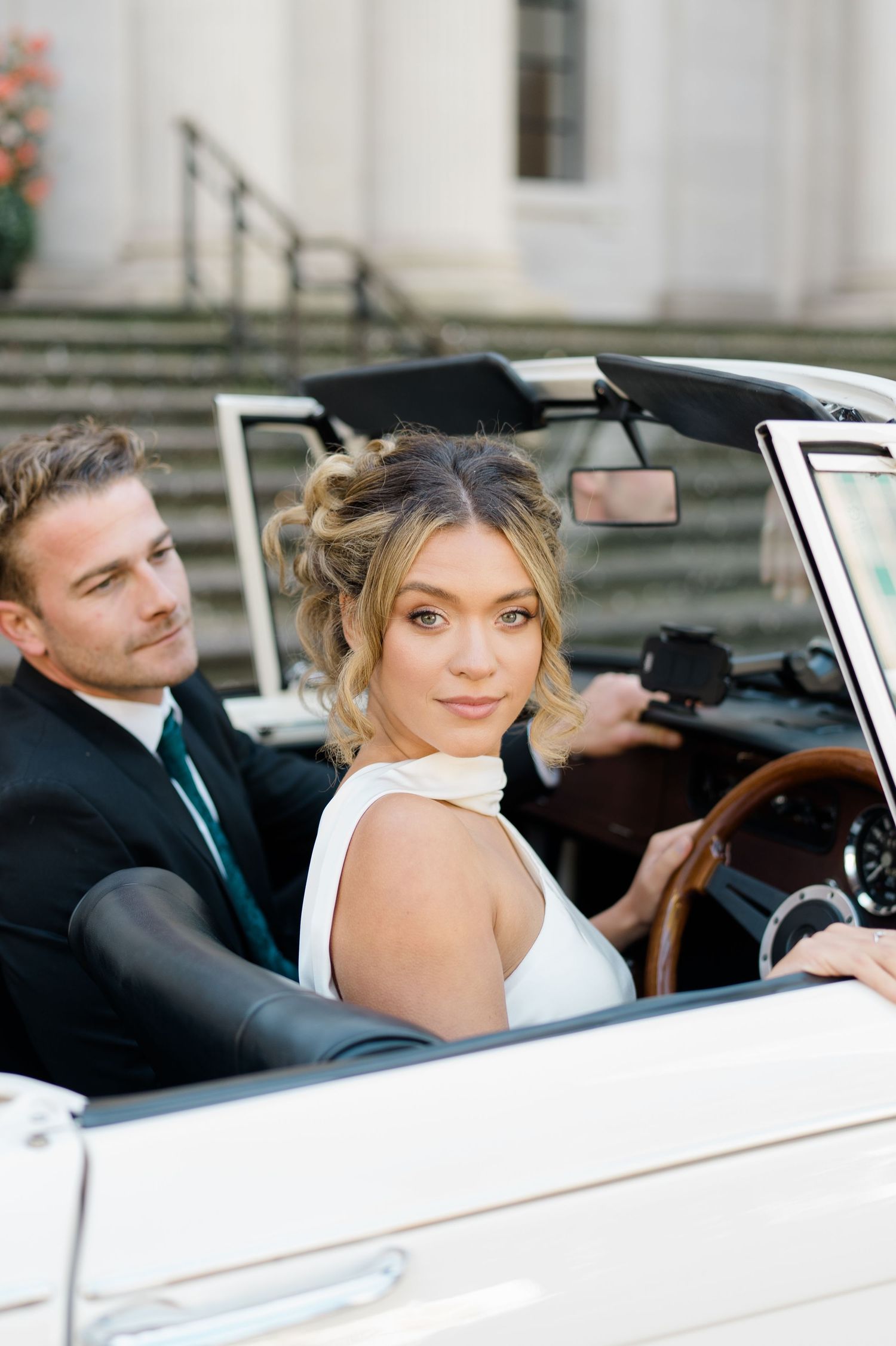Couple shares intimate moment in vintage white convertible car.