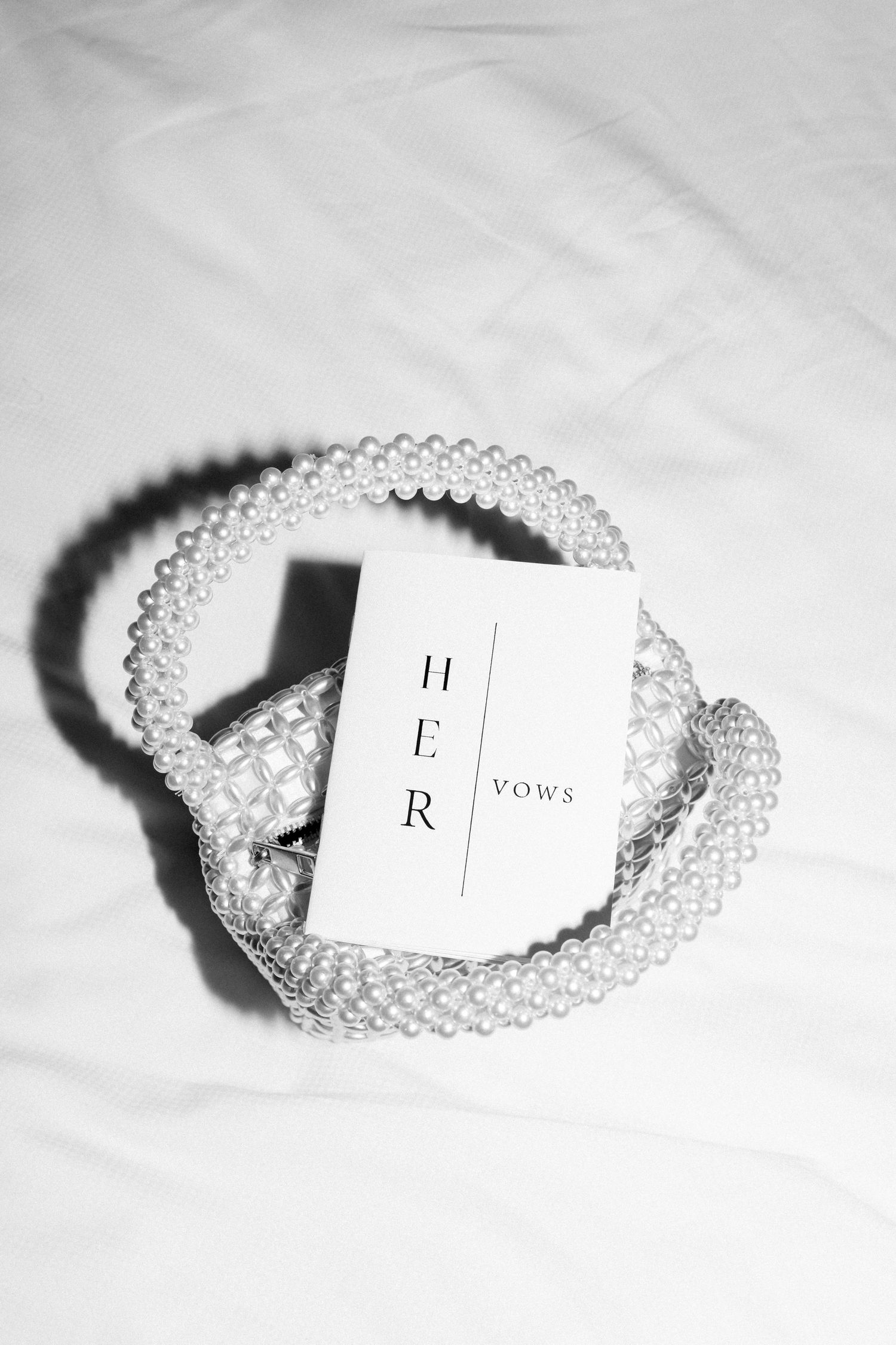 Pearl bracelets with small white cards displaying vows and wedding details against a light background.