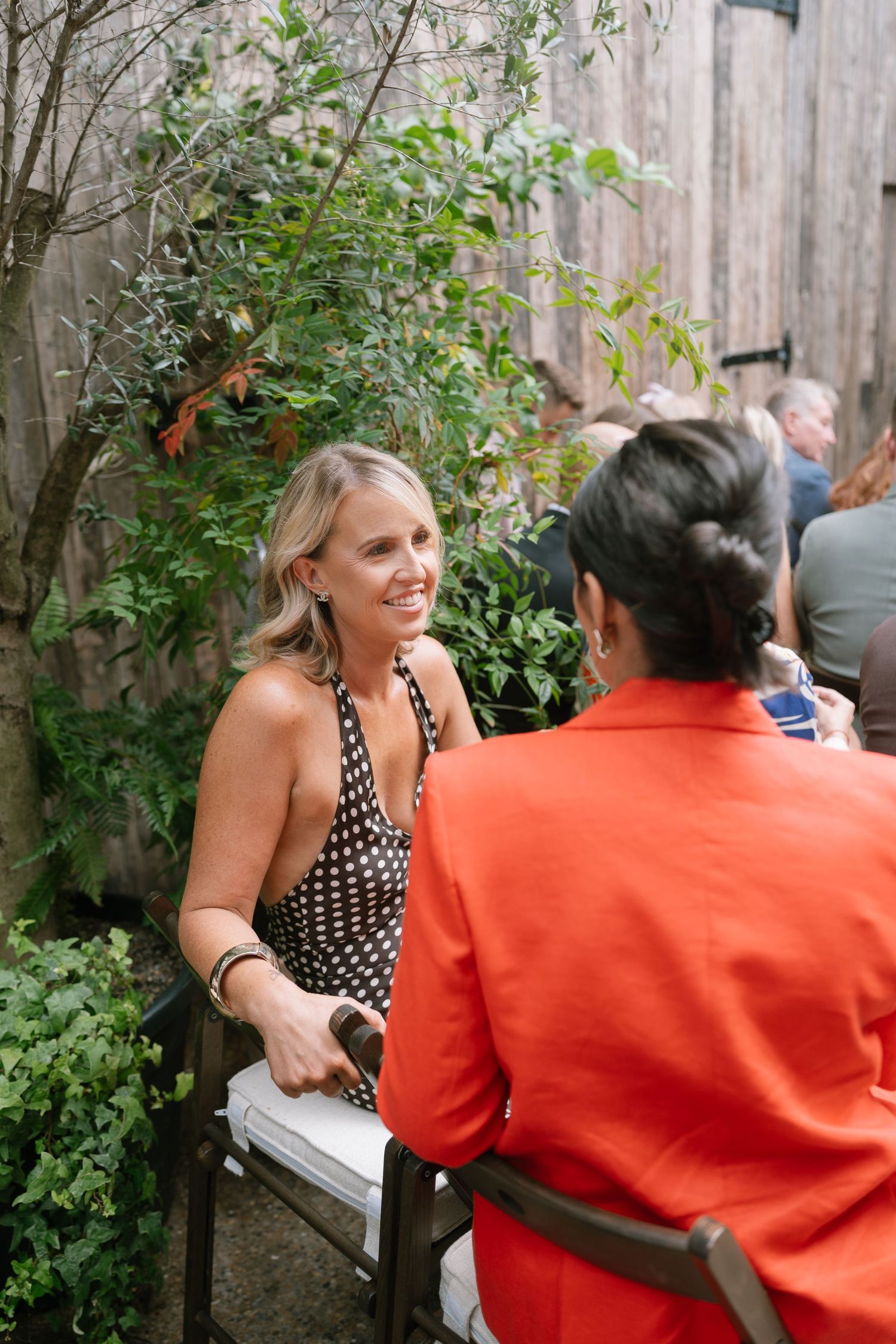Guests chatting and socializing on outdoor benches at a garden reception.