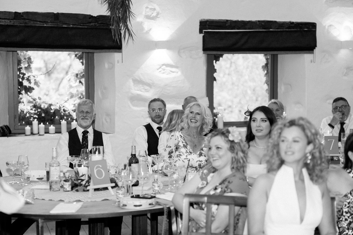 Black and white photo of wedding guests celebrating at reception tables.