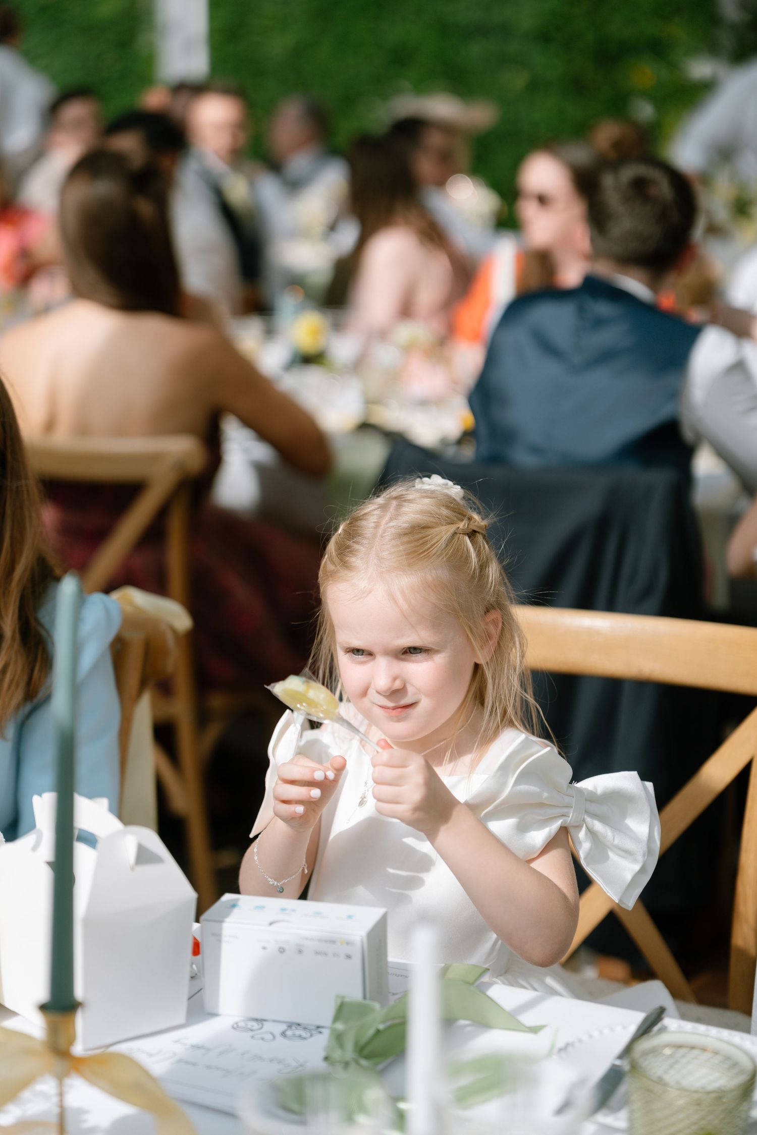 Children at an outdoor wedding reception table with white table settings.