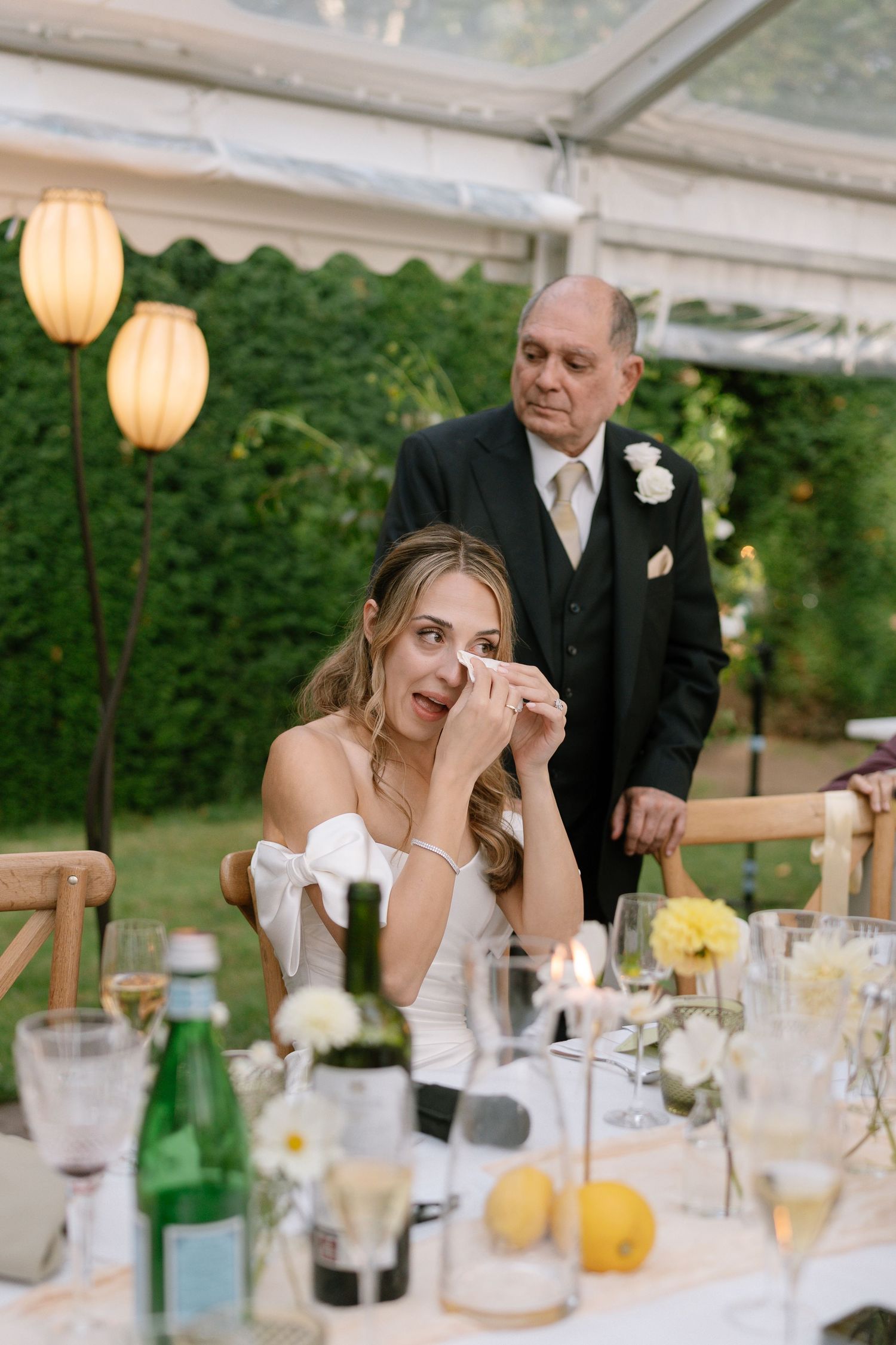 Emotional moment captured during wedding reception with elegant table settings and lantern decor.