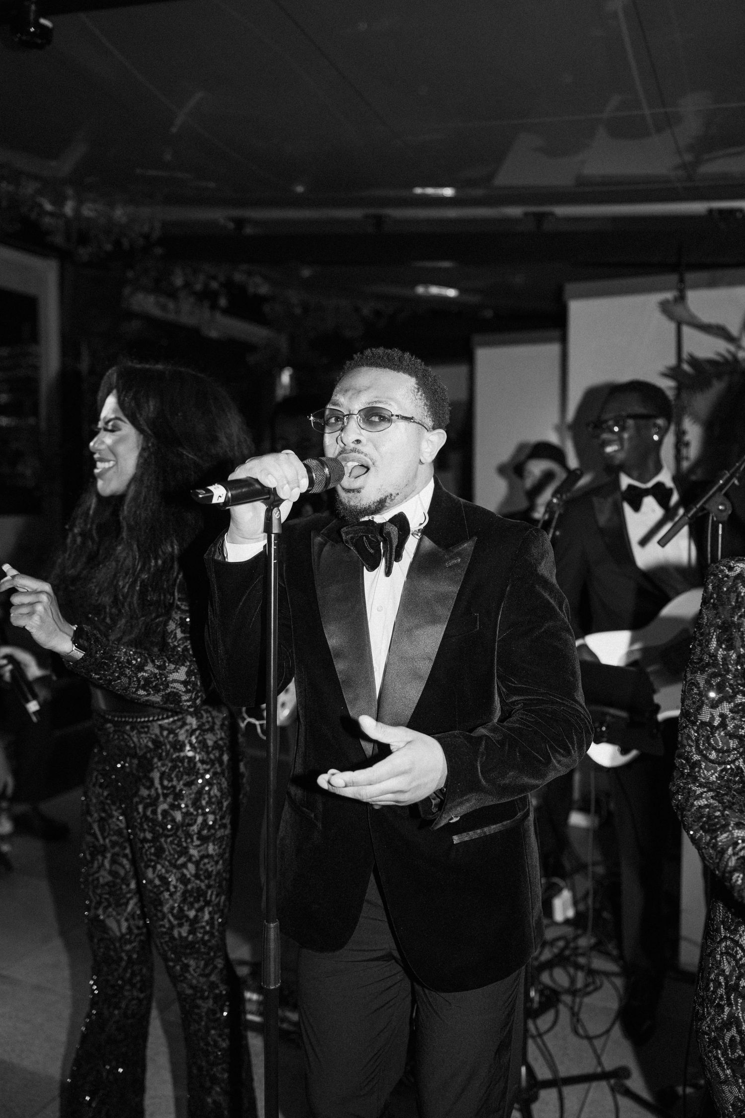 A group of performers in formal attire singing and dancing during an elegant event.