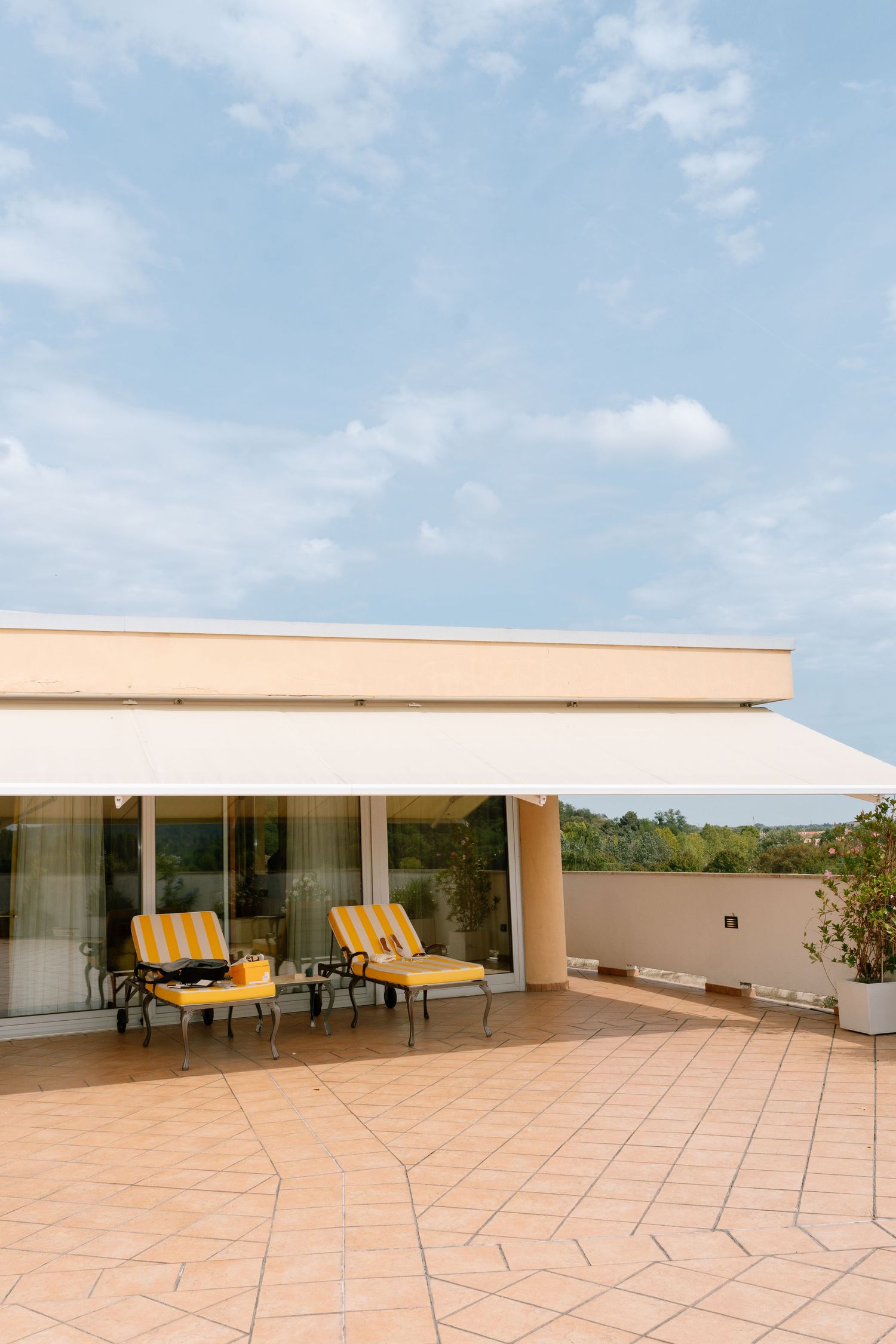 Modern terrace with yellow lounge chairs and white awning against blue sky.