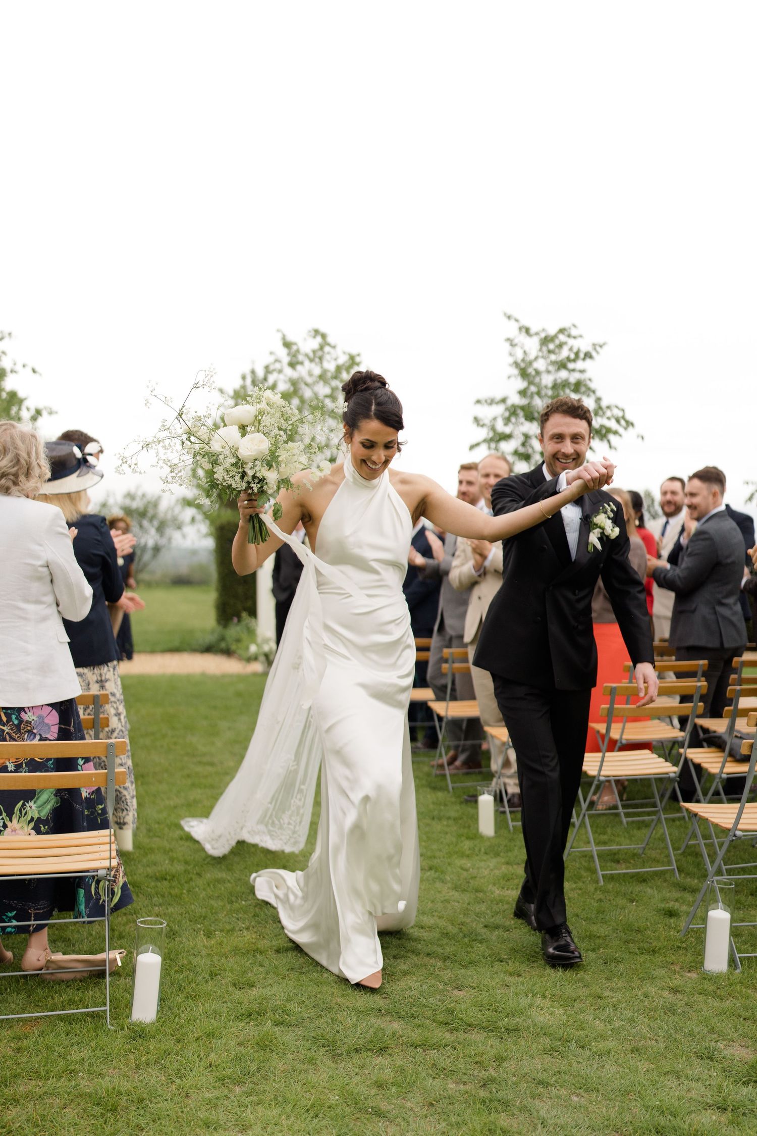 Bride and groom walking back down the aisle after wedding ceremony on green lawn.