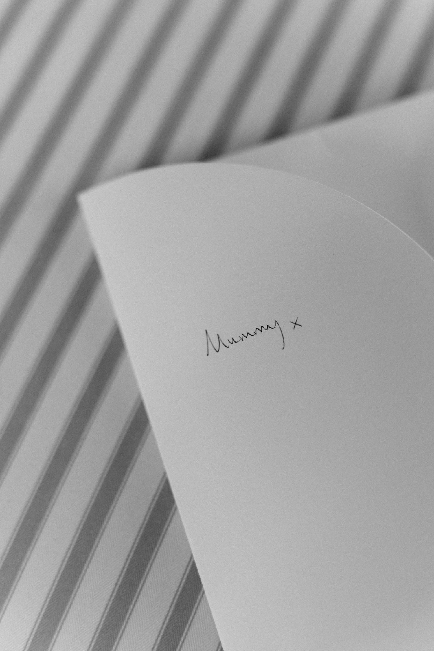 Handwritten note addressed to Mummy with a kiss on a white card at a wedding.