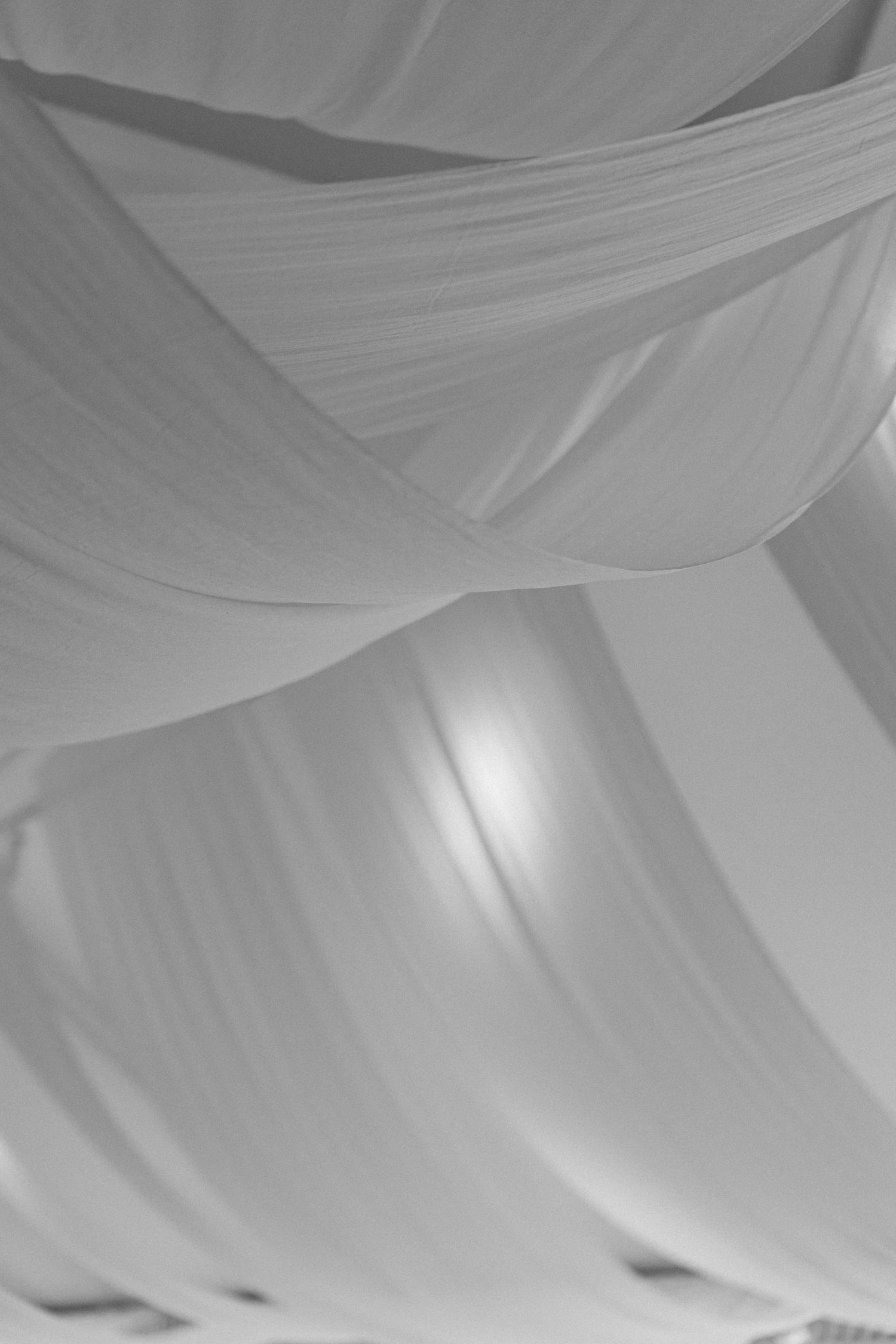 Black and white abstract close-up of draped white fabric ceiling at elegant wedding reception.
