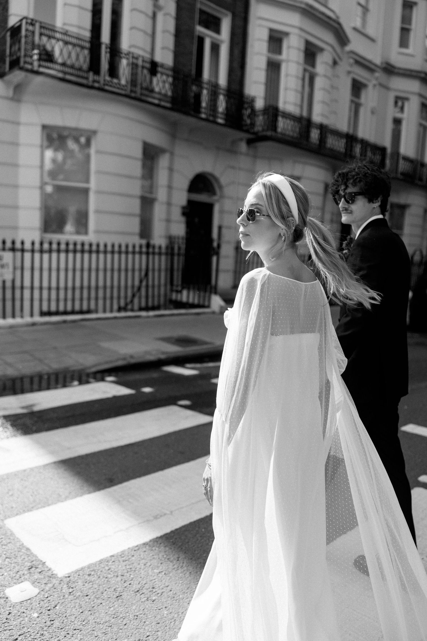 Wedding couple in sunlight creating dramatic shadows on an urban crosswalk.