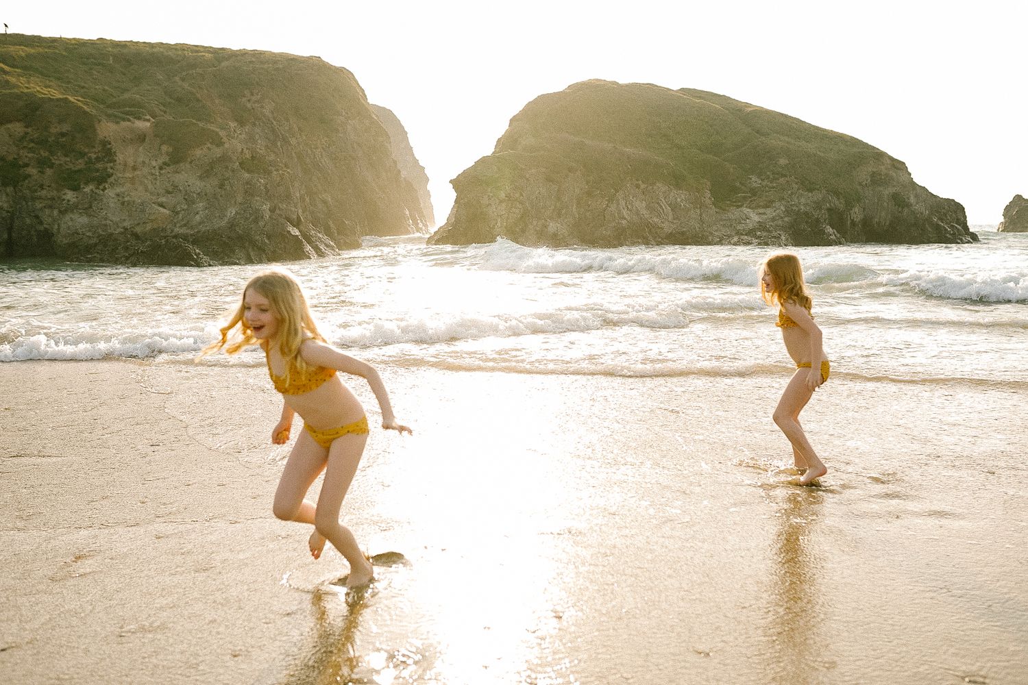 Silhouettes of people running and playing on beach at golden hour.