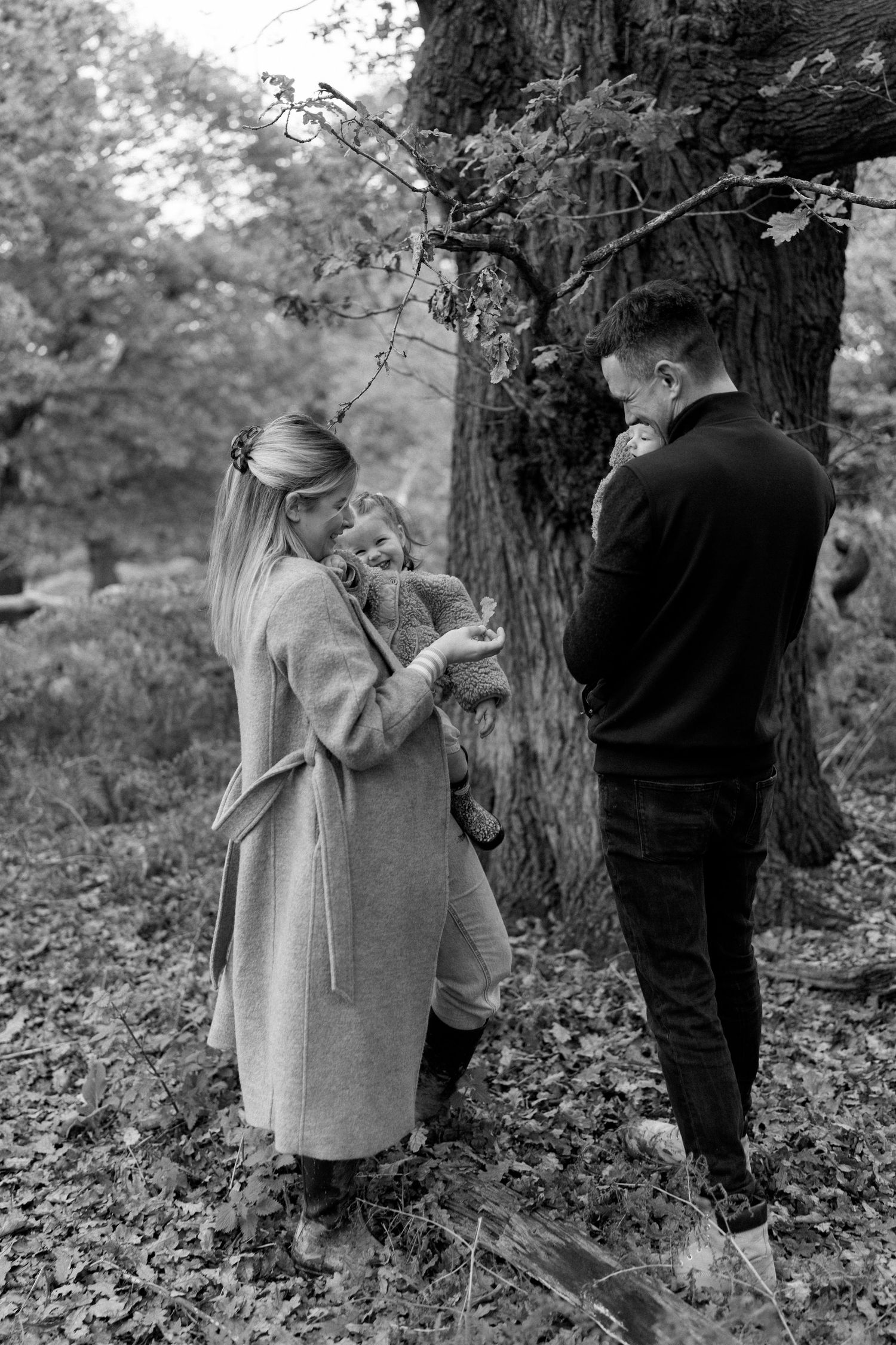 Family members share intimate moments in a wooded area during fall.