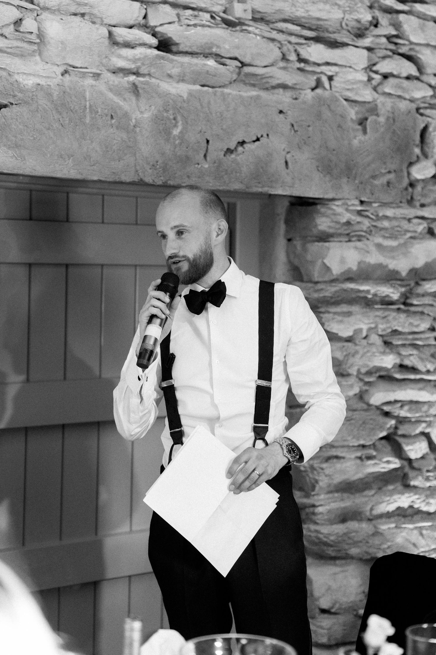 A series of black and white photos showing someone in formal attire posing against a stone wall.