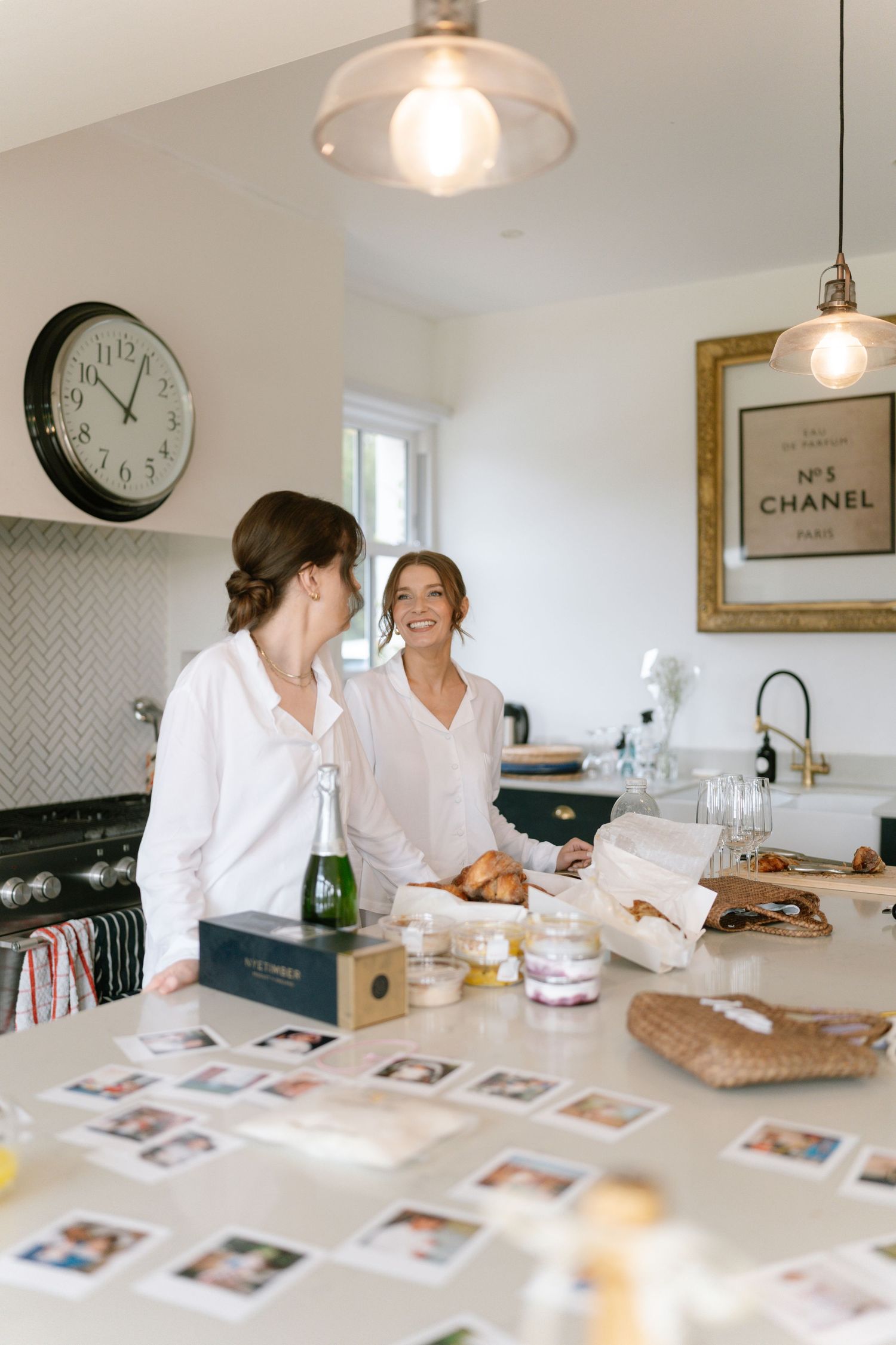 Beauty professionals reviewing materials at bright kitchen counter with pendant lighting.