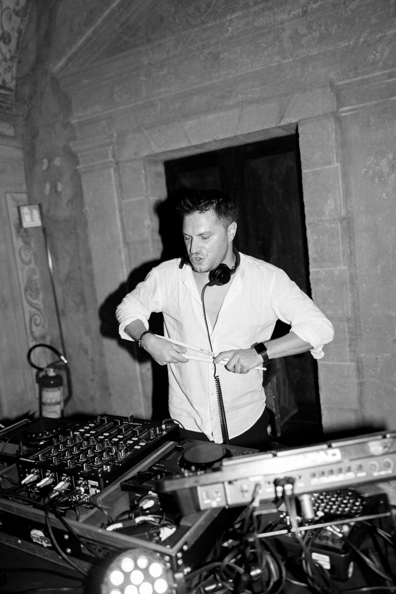 DJ working at mixing console during nightclub event in black and white.