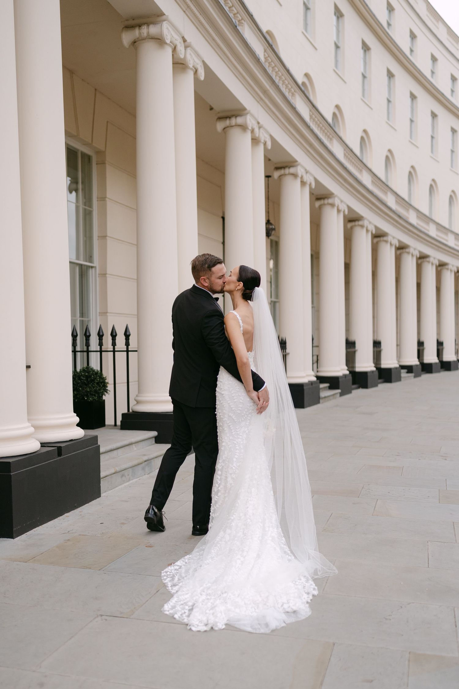 A romantic wedding moment captured against a backdrop of elegant white columns.