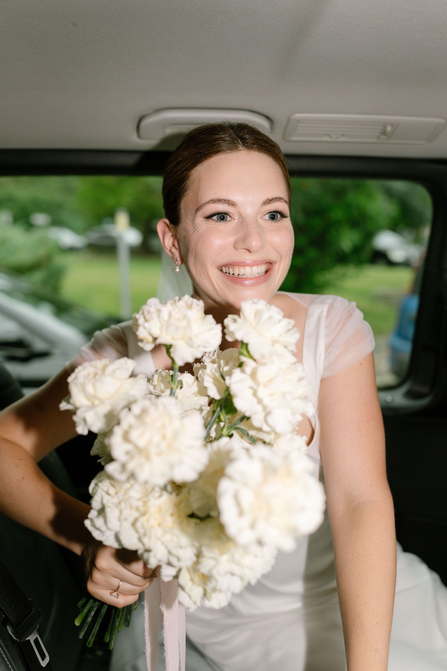 Close-up shots of someone holding a white floral bouquet in a car.