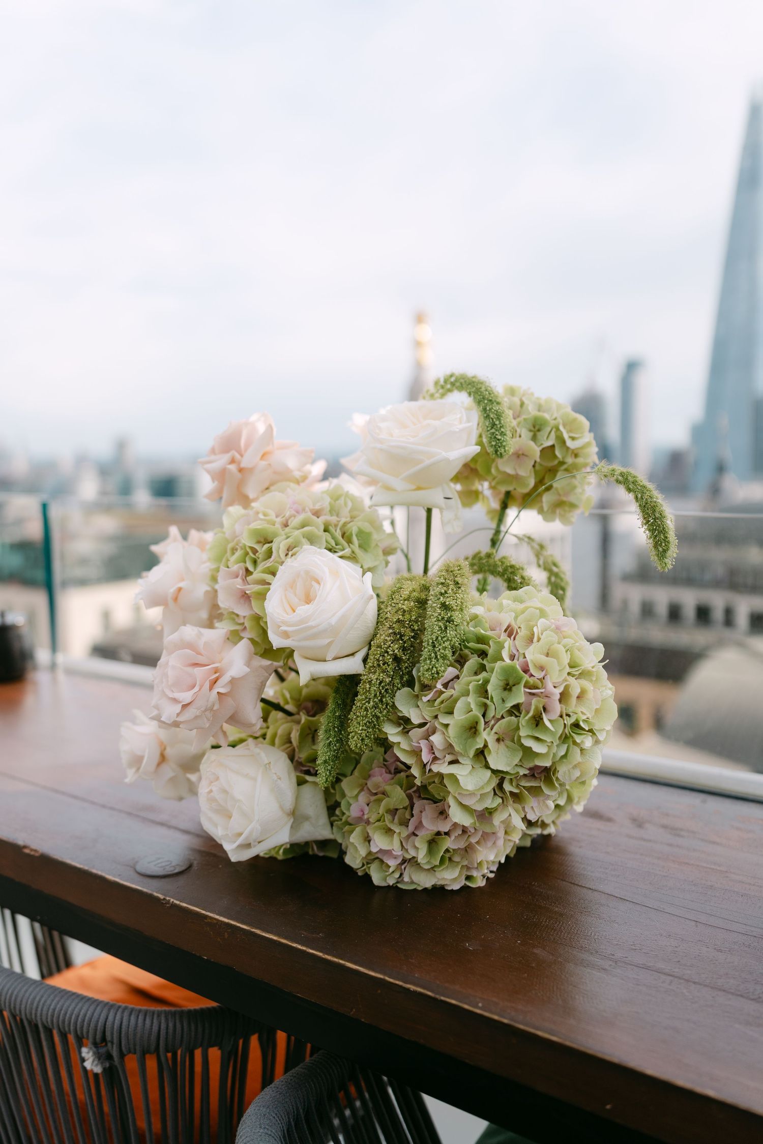Elegant wedding flower arrangement with white roses and hydrangeas against London skyline.