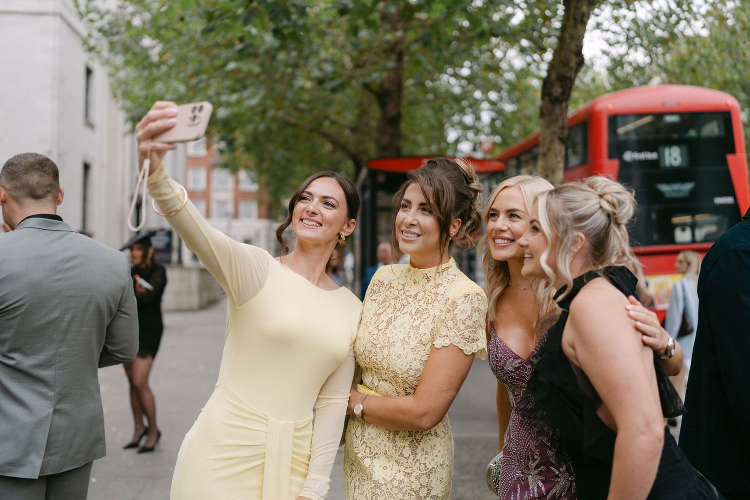 Wedding guests smile and pose for photos at an outdoor reception.