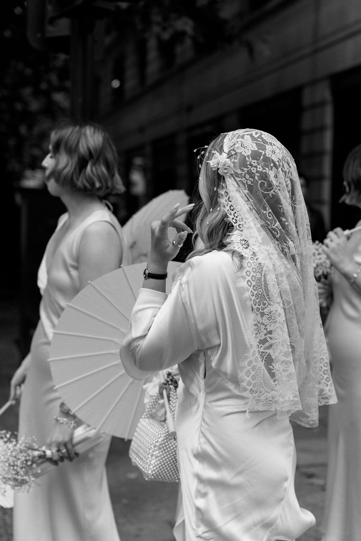 Black and white sequence of people in white dresses with lace veils.