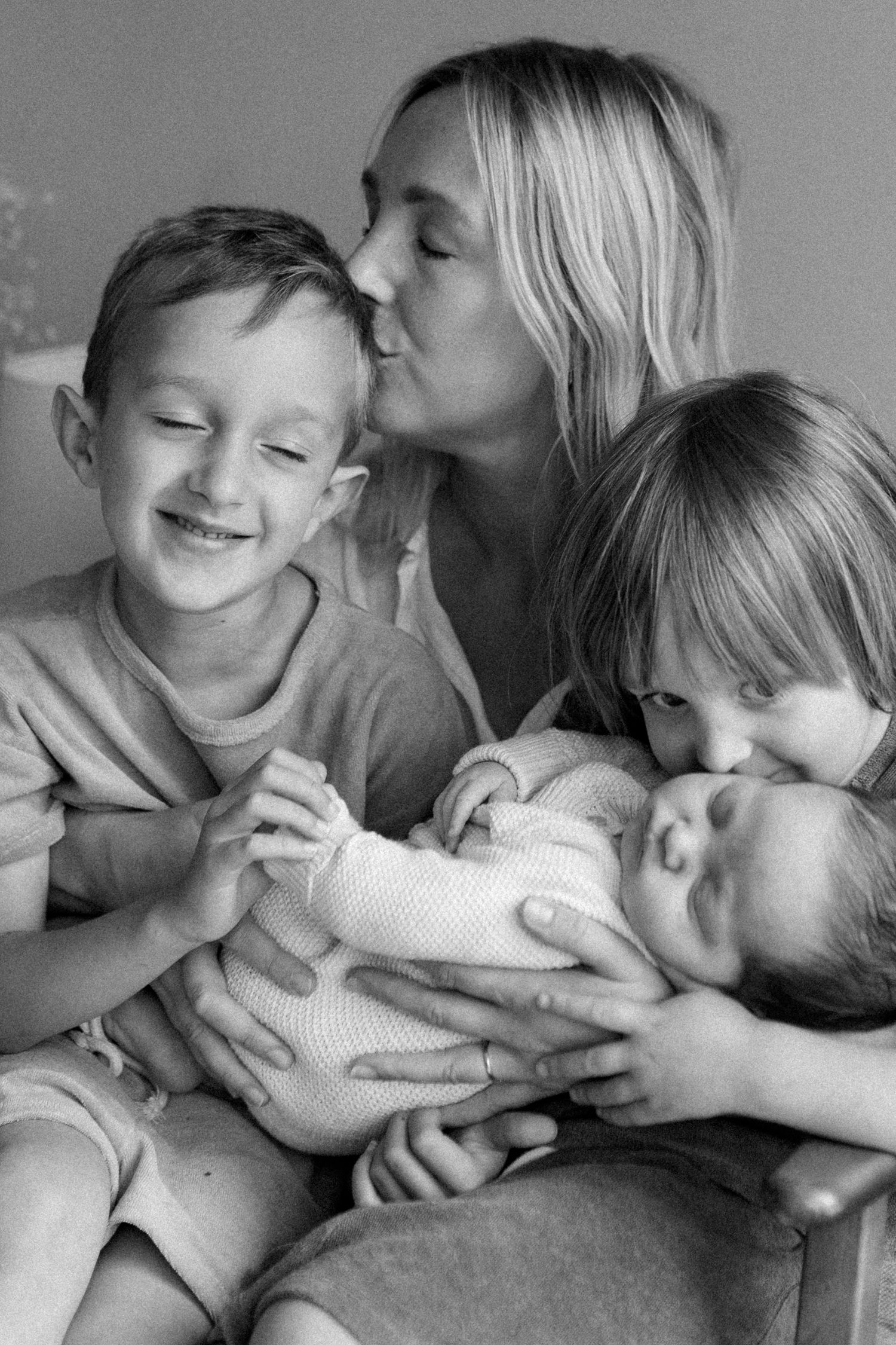 A black and white photo series shows a tender family moment with playful kisses and laughter between parent and child.