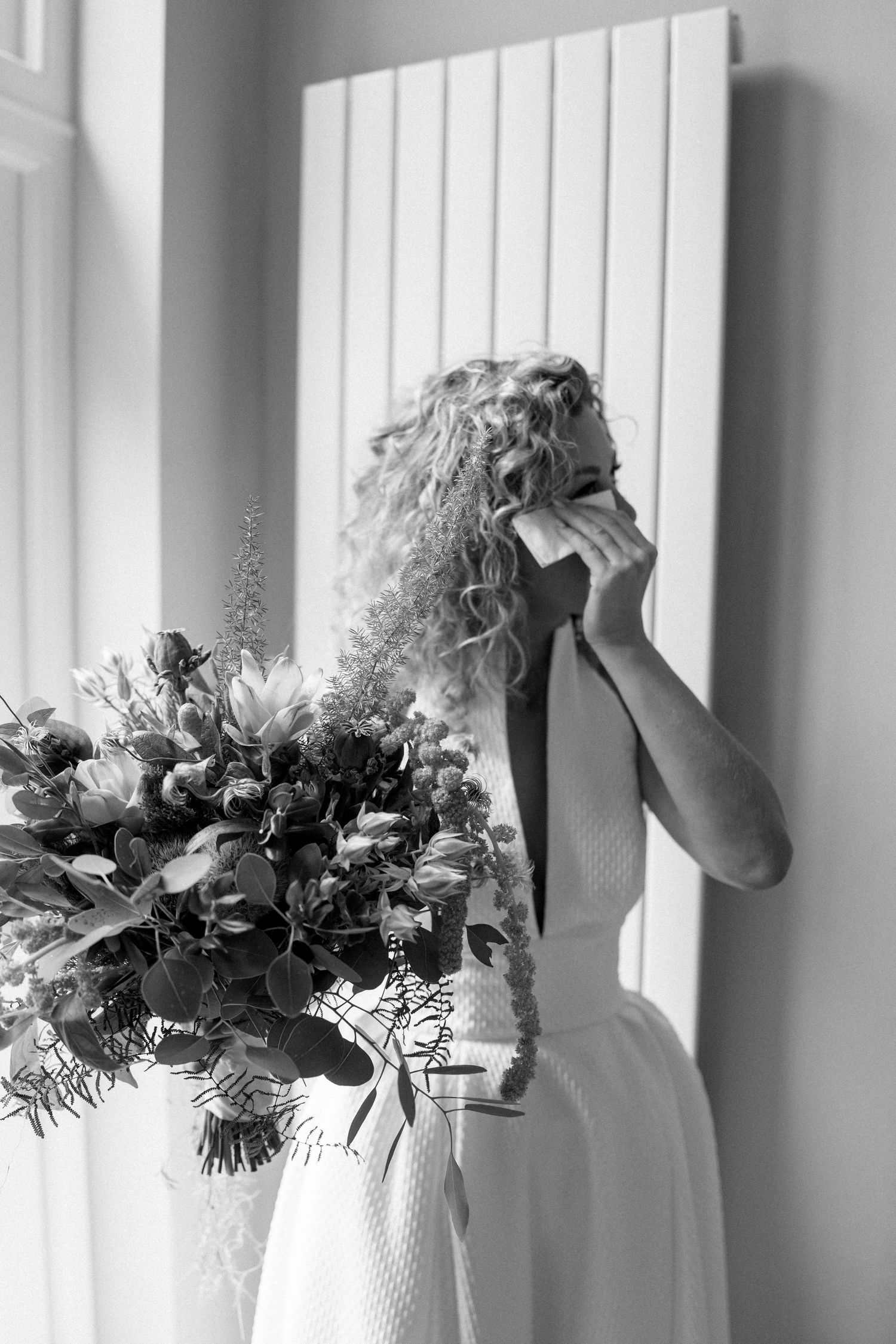 Wedding bouquets arranged in a row against a bright window creating an elegant black and white composition.
