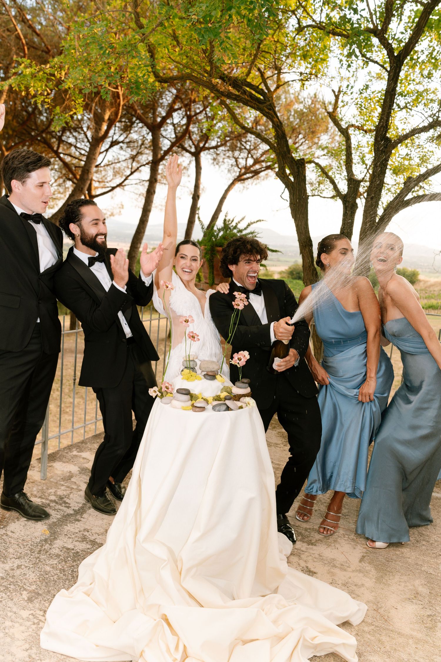 Wedding celebration with guests in blue dresses and formal attire dancing outdoors.