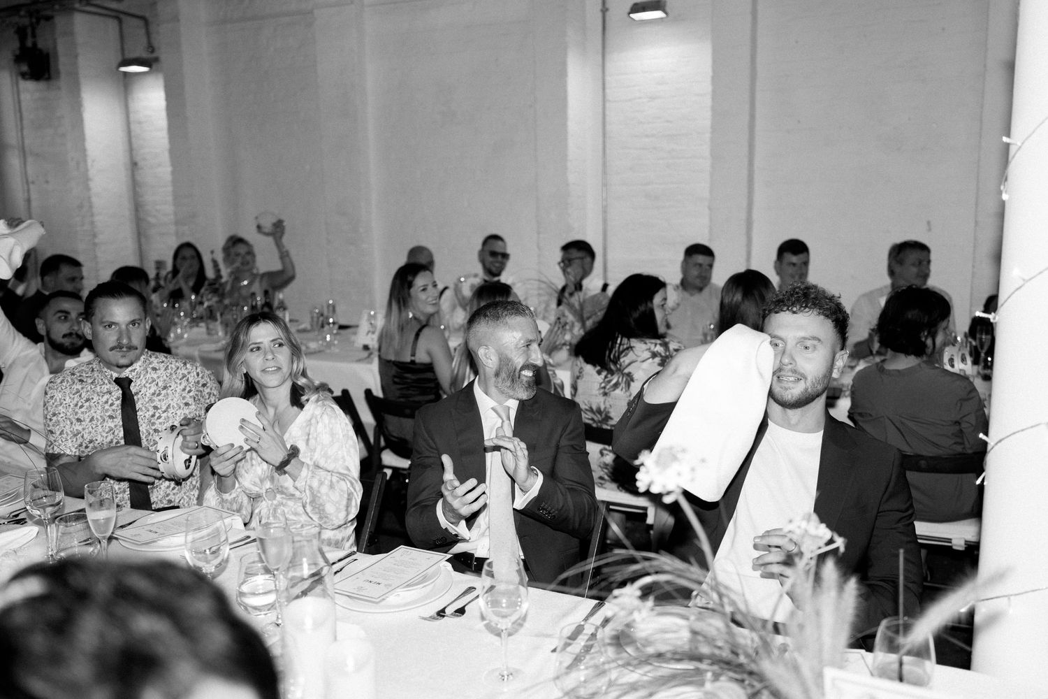 Reception dinner tables filled with guests in a bright indoor venue space.