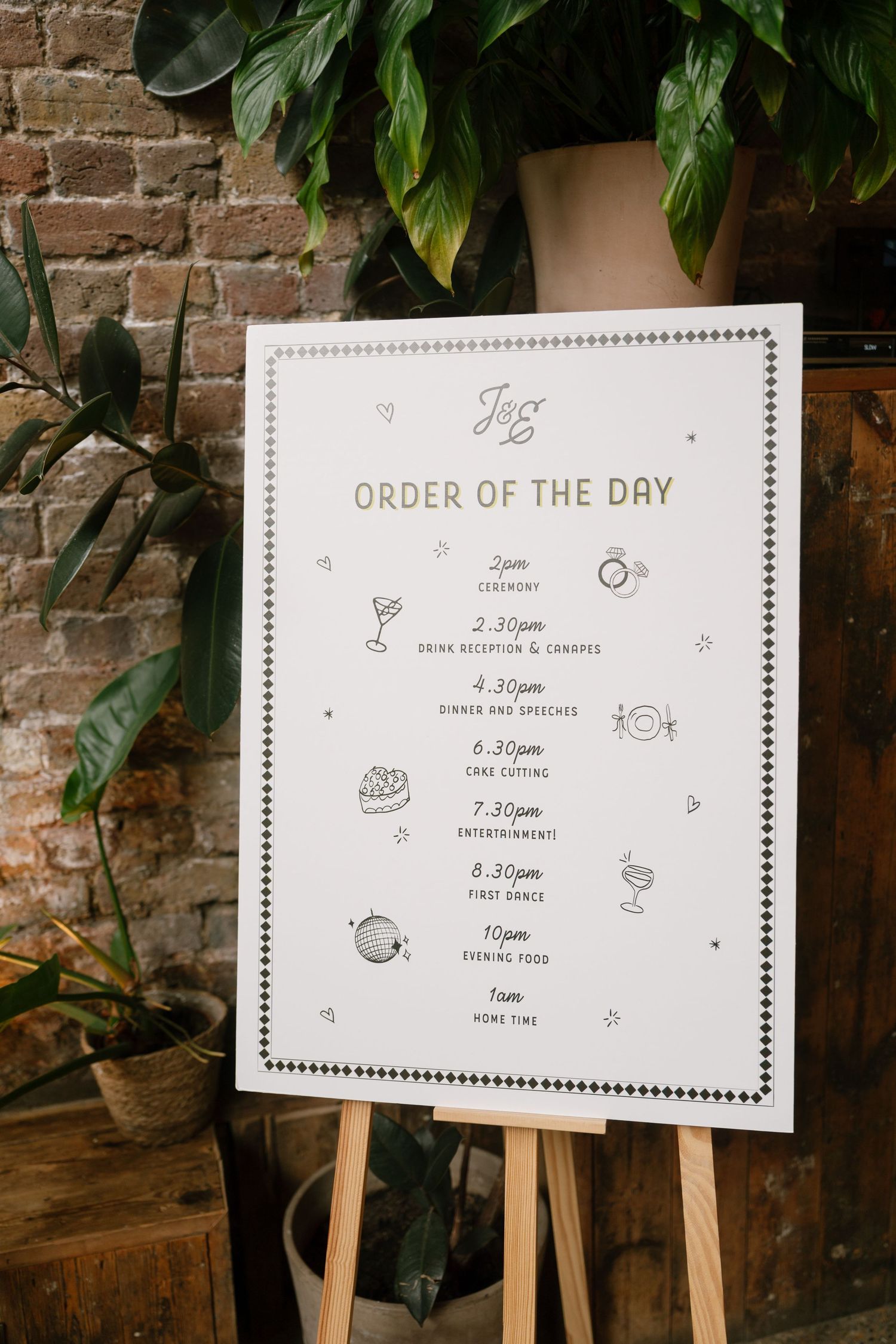 Wedding day schedule signs displayed on wooden easels against a brick wall.