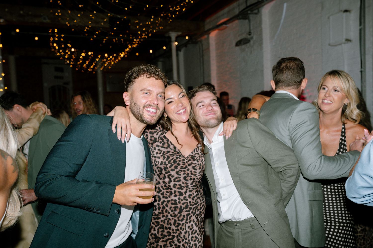 Wedding reception celebration with guests dancing under string lights.